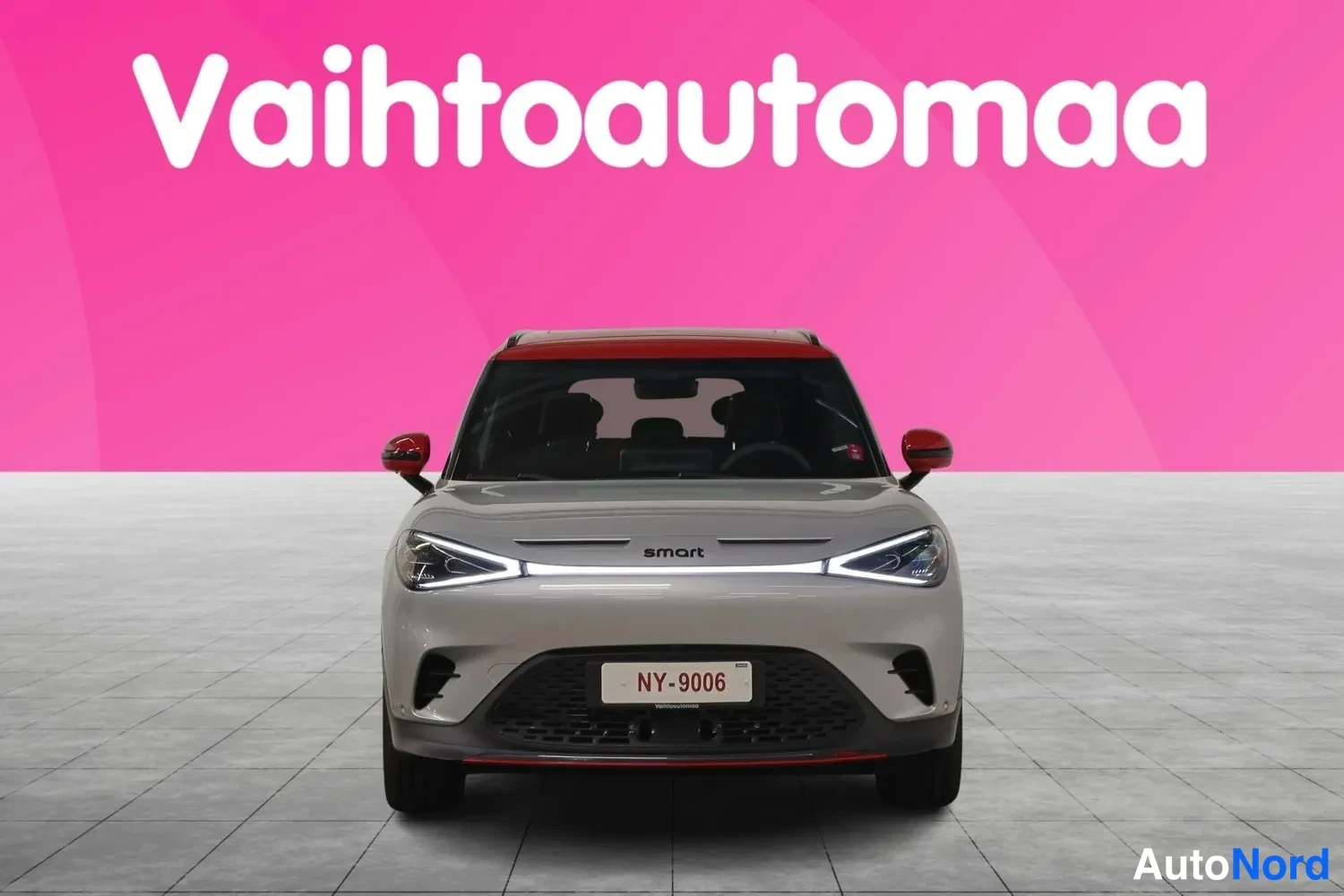 Edestä: Hopeanharmaa Smart-auto suoraan edestä, punainen katto ja rekisteri NY-9006.