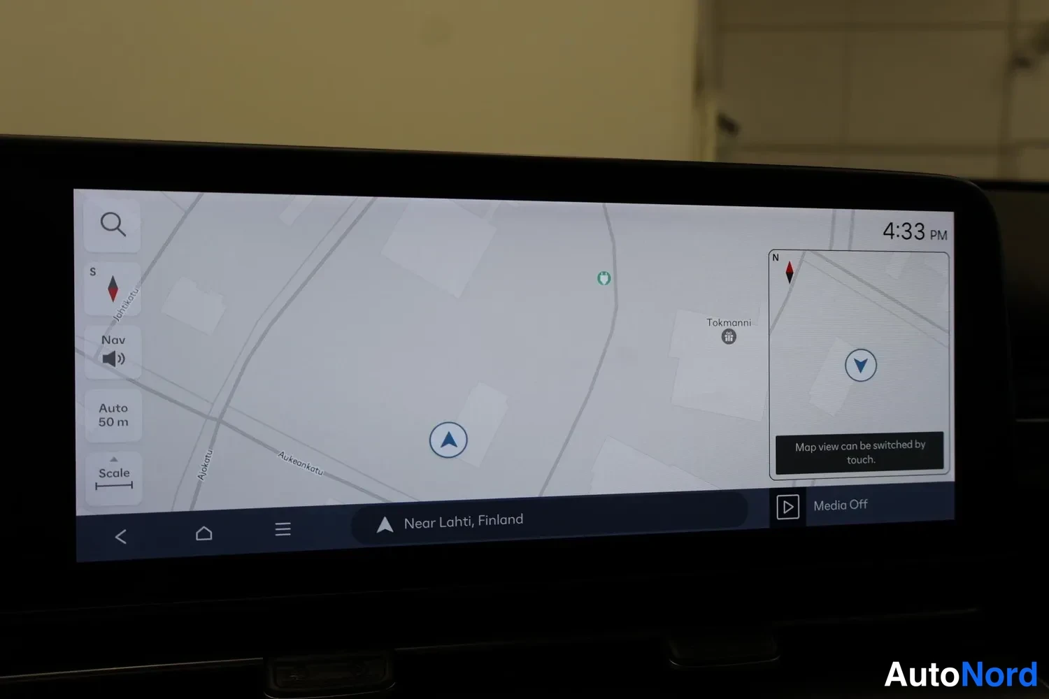 Yksityiskohta: Infotainment-näytön kartta (Near Lahti, Finland), vasemmassa valikossa Nav, Auto 50 m ja Scale, oikealla kellonaika 4:33 PM ja pienoiskartta.