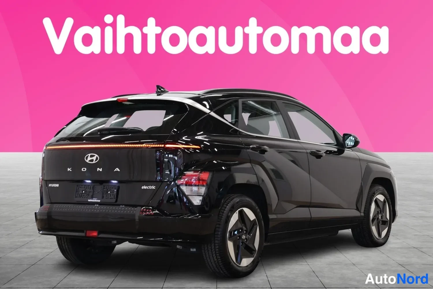 Takaviisto: Musta Hyundai Kona 3/4-takakulmasta, oikea kylki ja takapää näkyvissä, np-valojuova palaa.