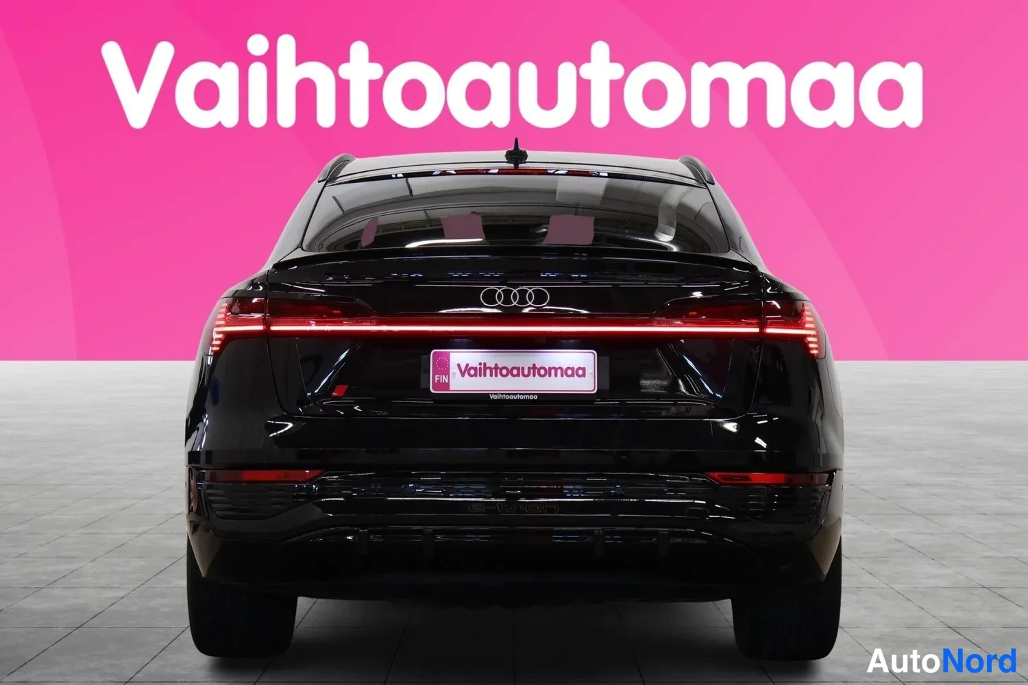 Takaa: Mustan Audi Suvin takapää suoraan edestä, LED-takavalot ja Vaihtoautomaata-merkki päällä.