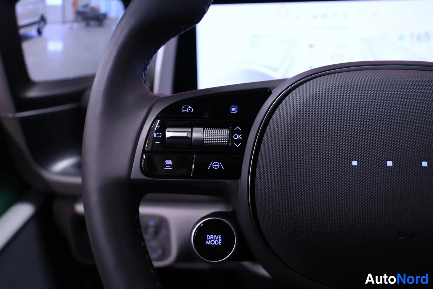 Yksityiskohta: Ratin vasemman puolen painikkeet lähikuvassa:Driver Assistance -näppäimet ja DRIVE MODE -nappi.