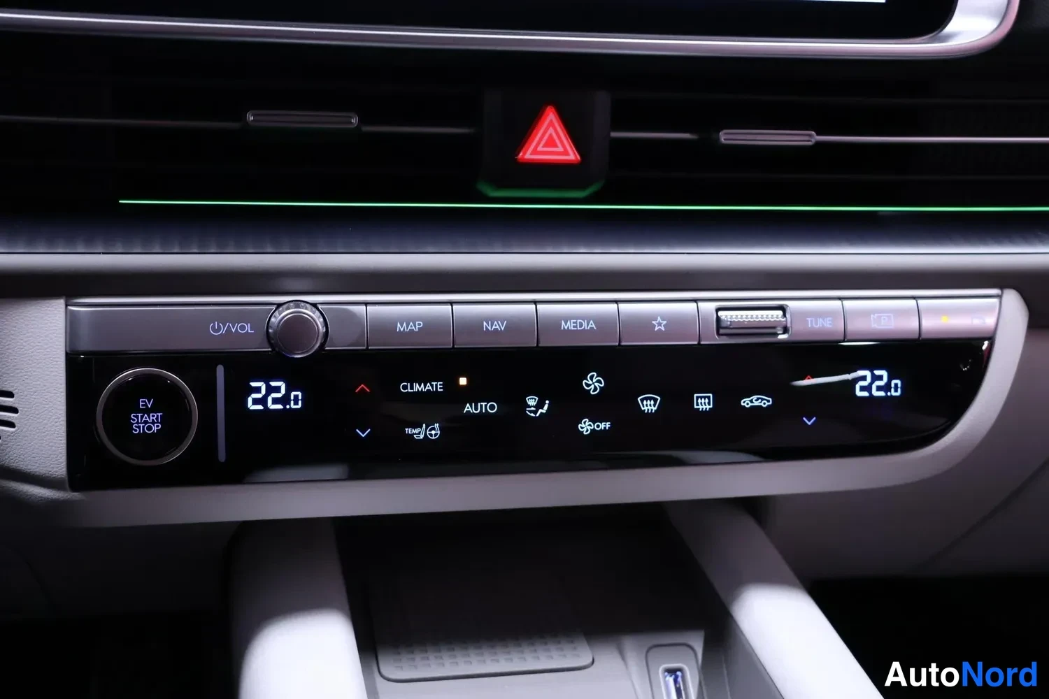 Ohjaamo: Close-up of center console controls including climate system displaying 22.0 degrees on both sides and illuminated push-buttons labeled MAP, NAV, MEDIA
