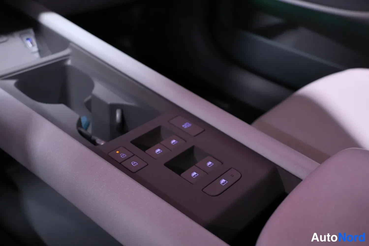 Ohjaamo: View of driver-side door panel armrest housing window switches with blue backlighting and lock/unlock buttons