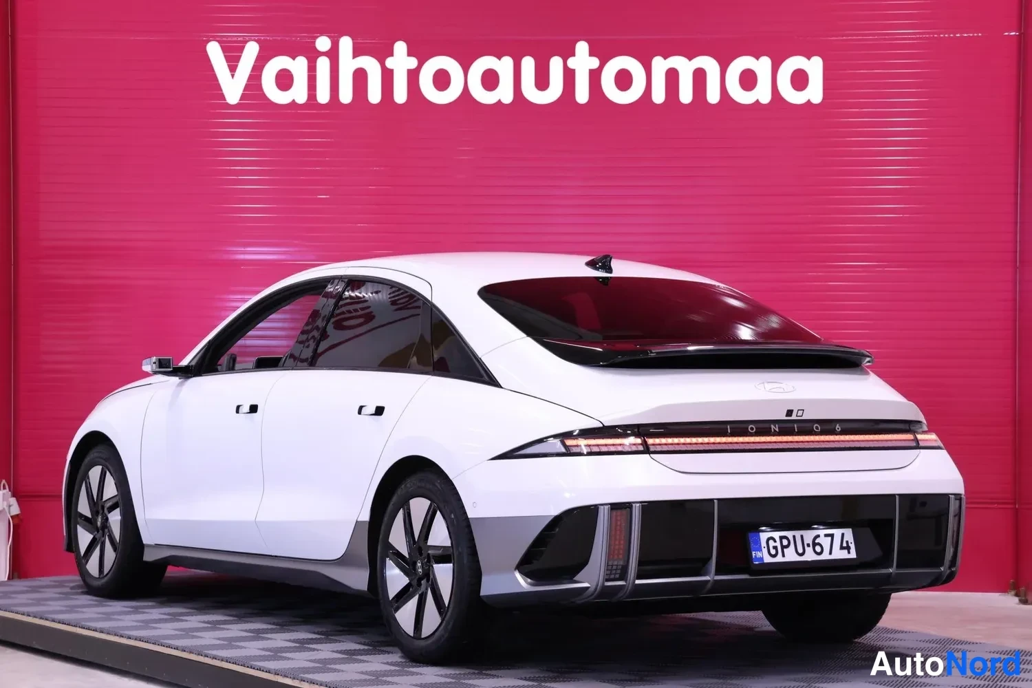 Takaviisto: Auton takaosa ja vasen kylki kolmannes­kulmasta, valkoinen korinpinta, rekisteritunnus.