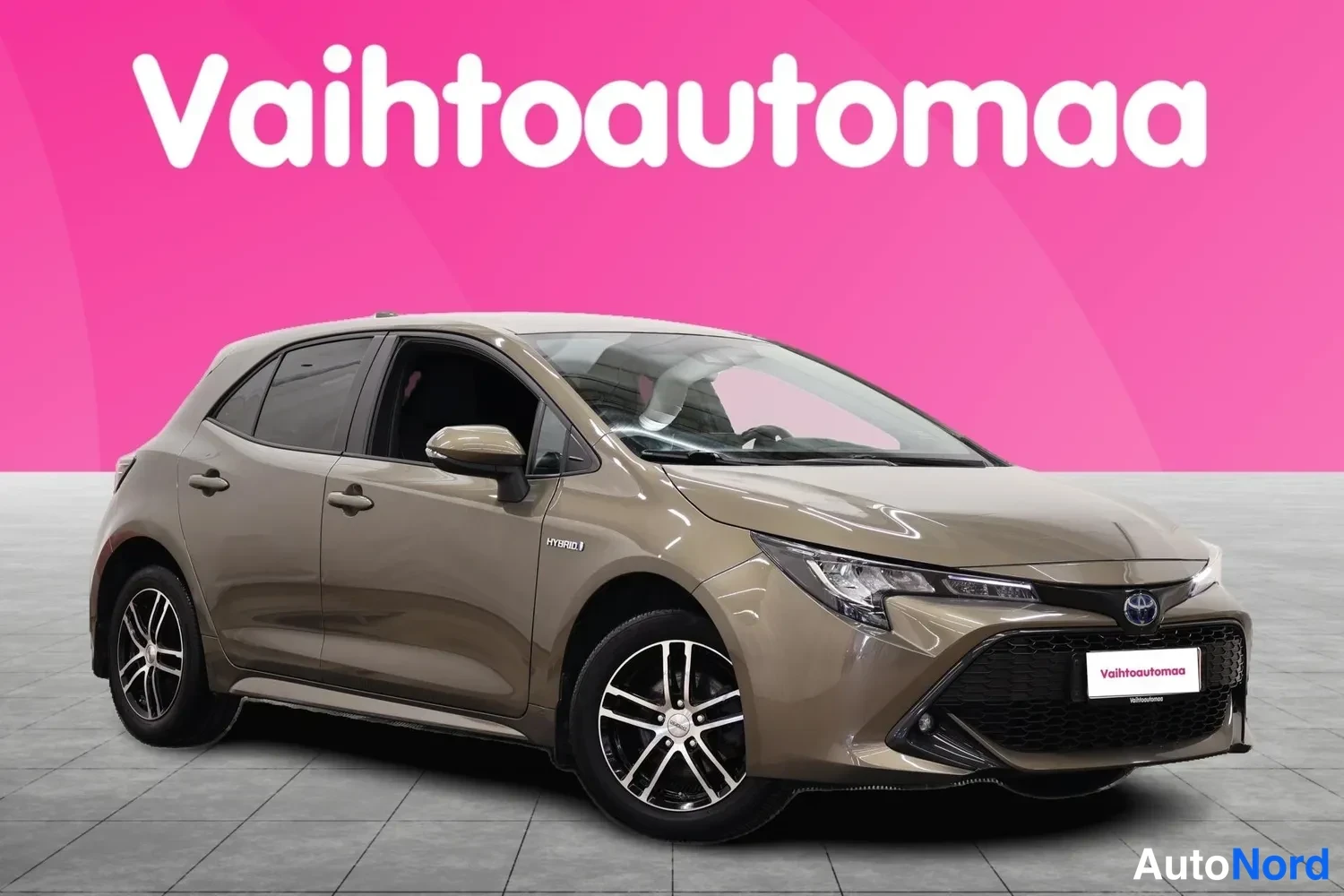 Etuviisto, nokka oikealle: Ruskean-beige viistoperä Toyota Corolla Hybrid etukulmasta oikealle suunnattuna, vaaleat vanteet