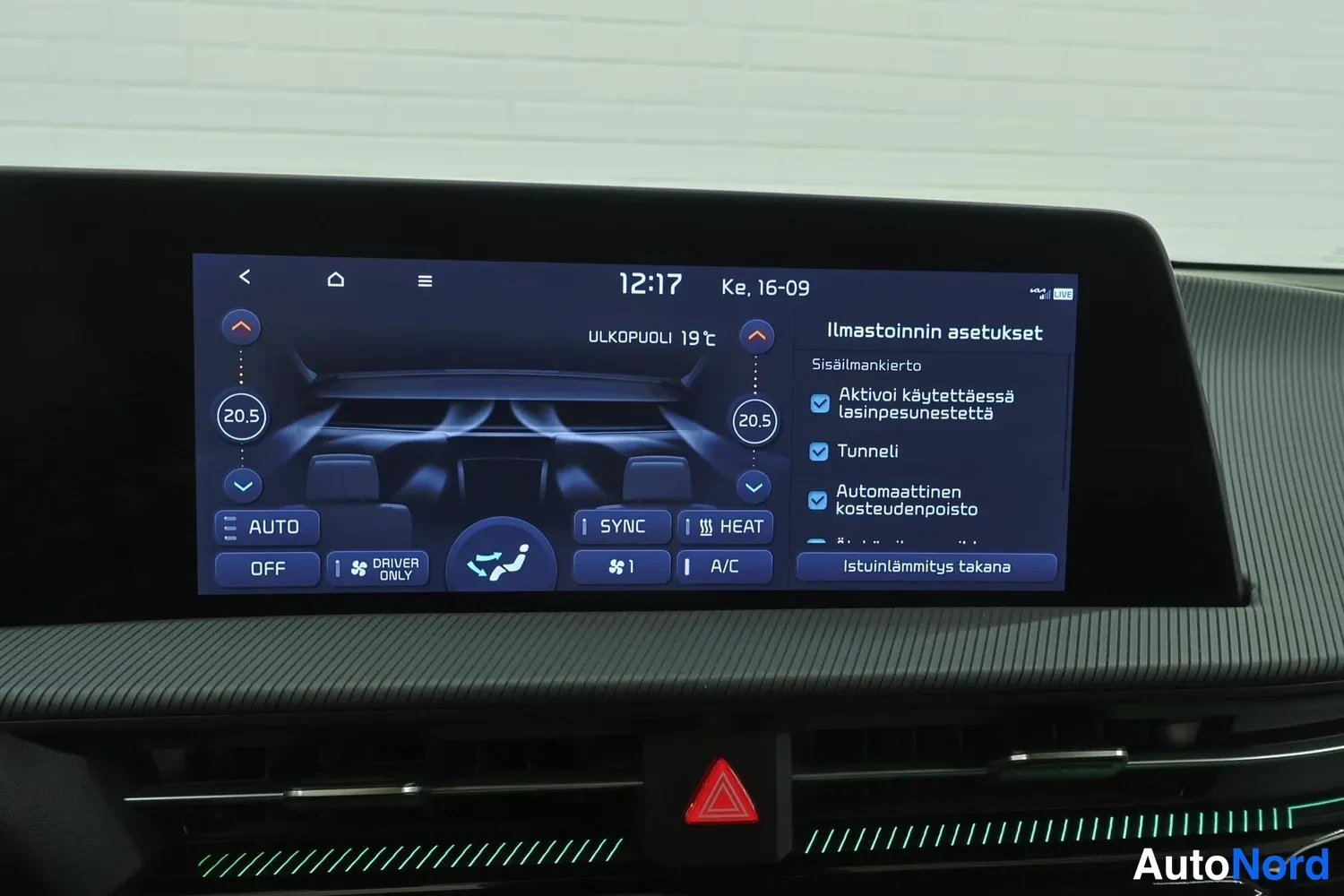Muu: Kojelaudan infotainment-näyttö näyttää ilmastoinnin asetuksia: molempien sivujen lämpötila 20,5 astetta, SYNC-, HEAT- ja A/C-toiminnot sekä istuinlämmitys takan