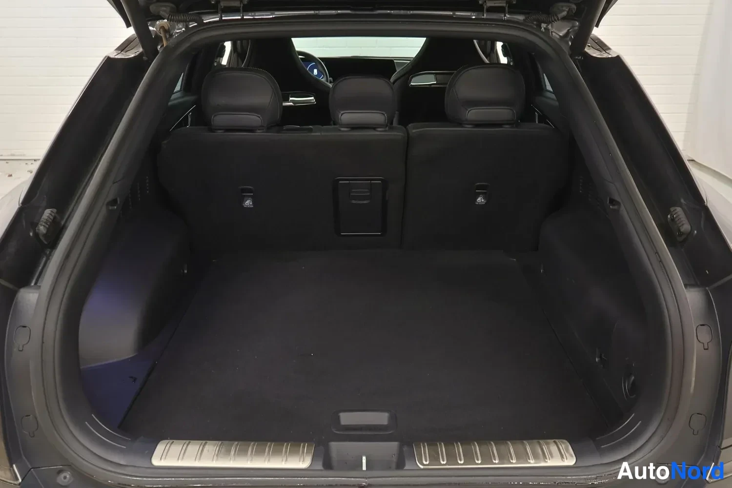 Tavaratila: Rear cargo area trunk of an SUV type vehicle viewed from behind with open tailgate; three rear seats are folded flat to create a large storage floor and headres