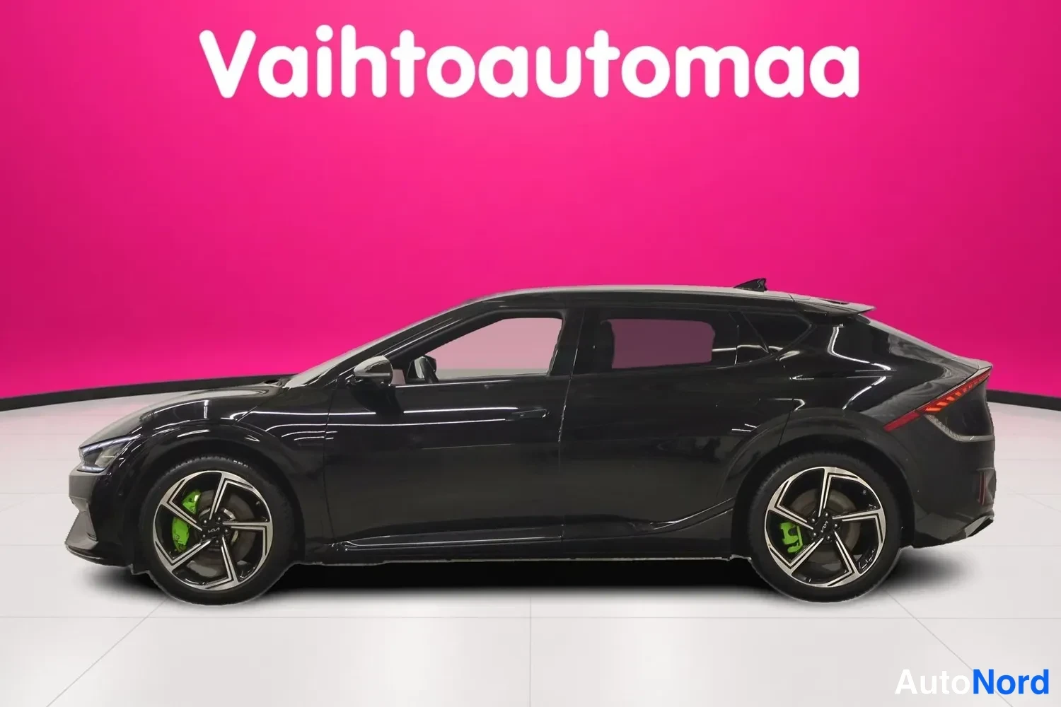 Sivulta: Mustan Kia EV6:n sivukuva vasemmalta, pyörät ja korin sivut näkyvät pinkkib taustaa vasten.