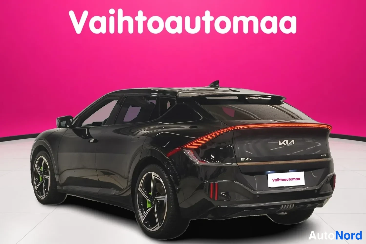 Takaviisto: Mustan Kia EV6:n taka­kulma oikealta, takavalot ja KIA-merkki näkyvät pinkkib taustaa vasten.