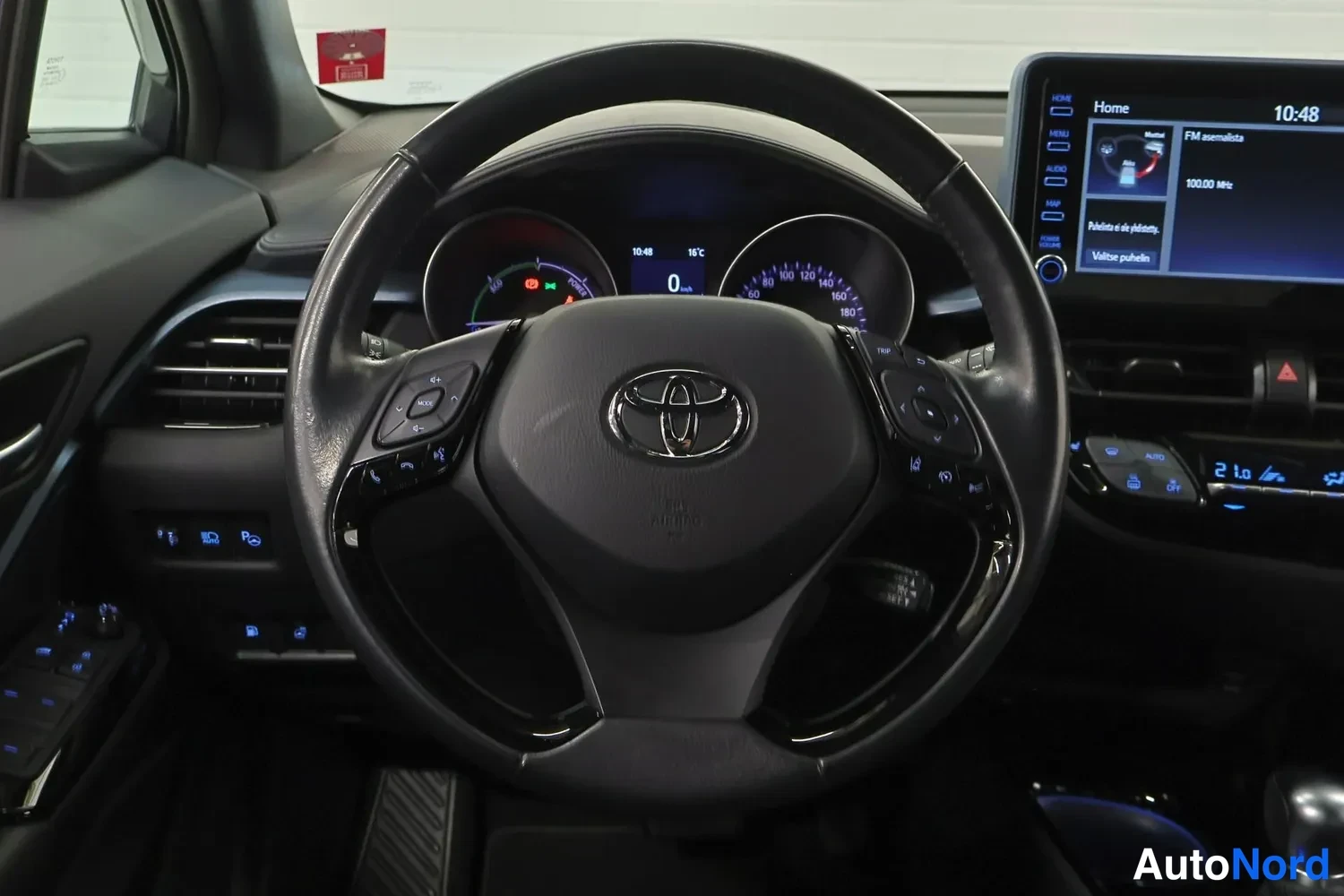Muu: Lähikuva Toyota-ohjauspyörästä ja mittaristosta, keskinäyttö näkyy oikealla reunalla.
