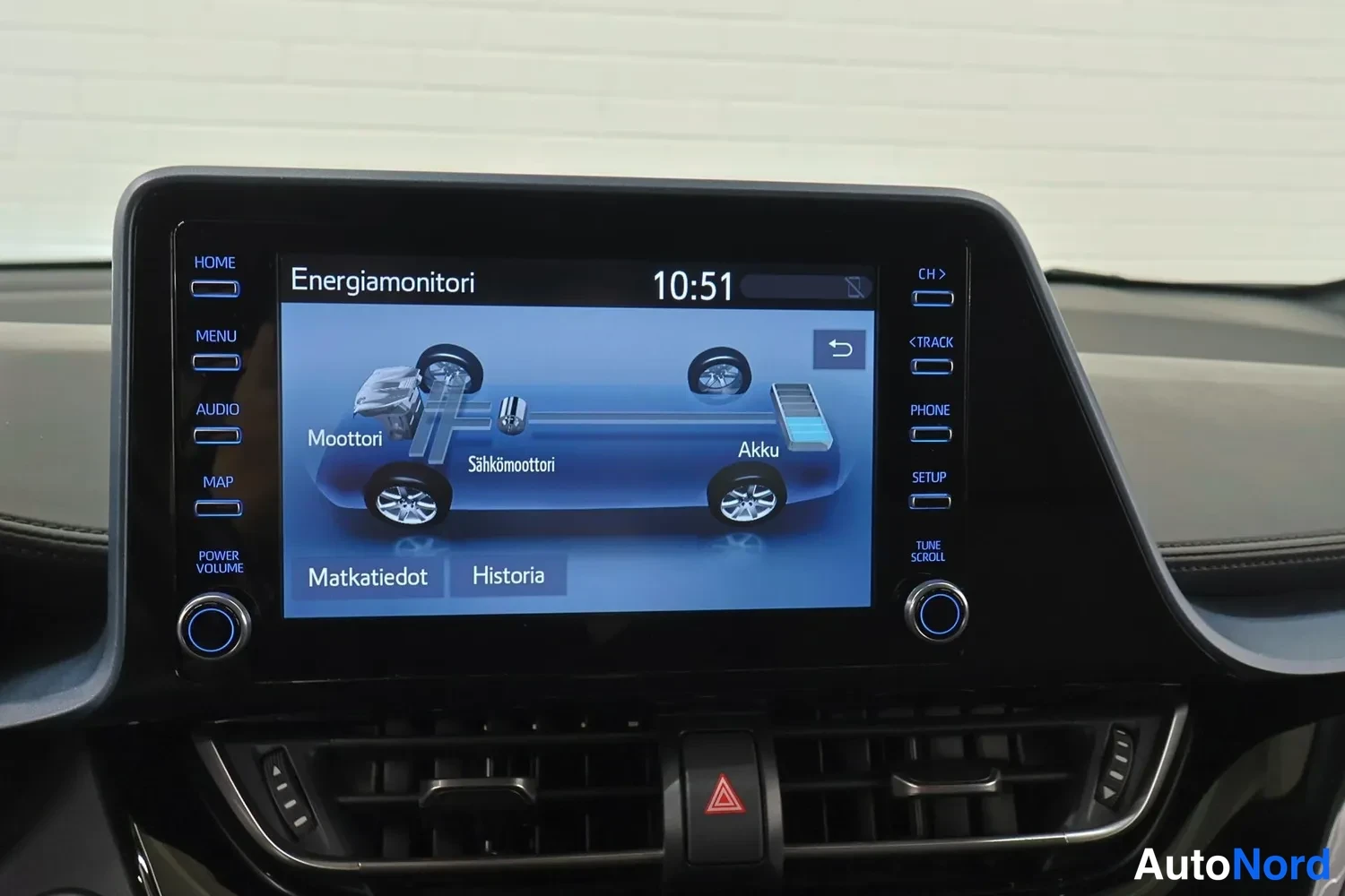 Muu: Kojelaudan infotainment-näyttö näyttää hybridin Energiamonitori-näkymän Moottori, Sähkömoottori ja Akku-merkinnöillä, kello 10:51.