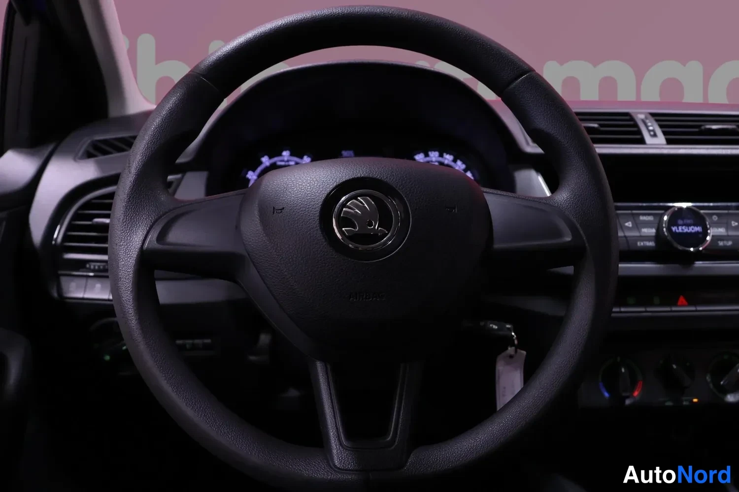 Muu: Ohjauspyörä ja kojelauta: Skoda-merkki ohjauspyörän keskellä, mittaristo ja radio taustalla näkyvissä.