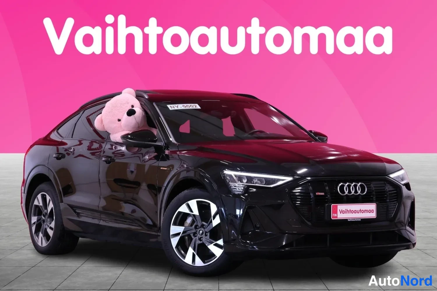 Etuviisto, nokka oikealle: Musta Audi e-tron Sportback vinosti edestä oikealta, keulakilpi ja rätti-ikoneja näkyvät.