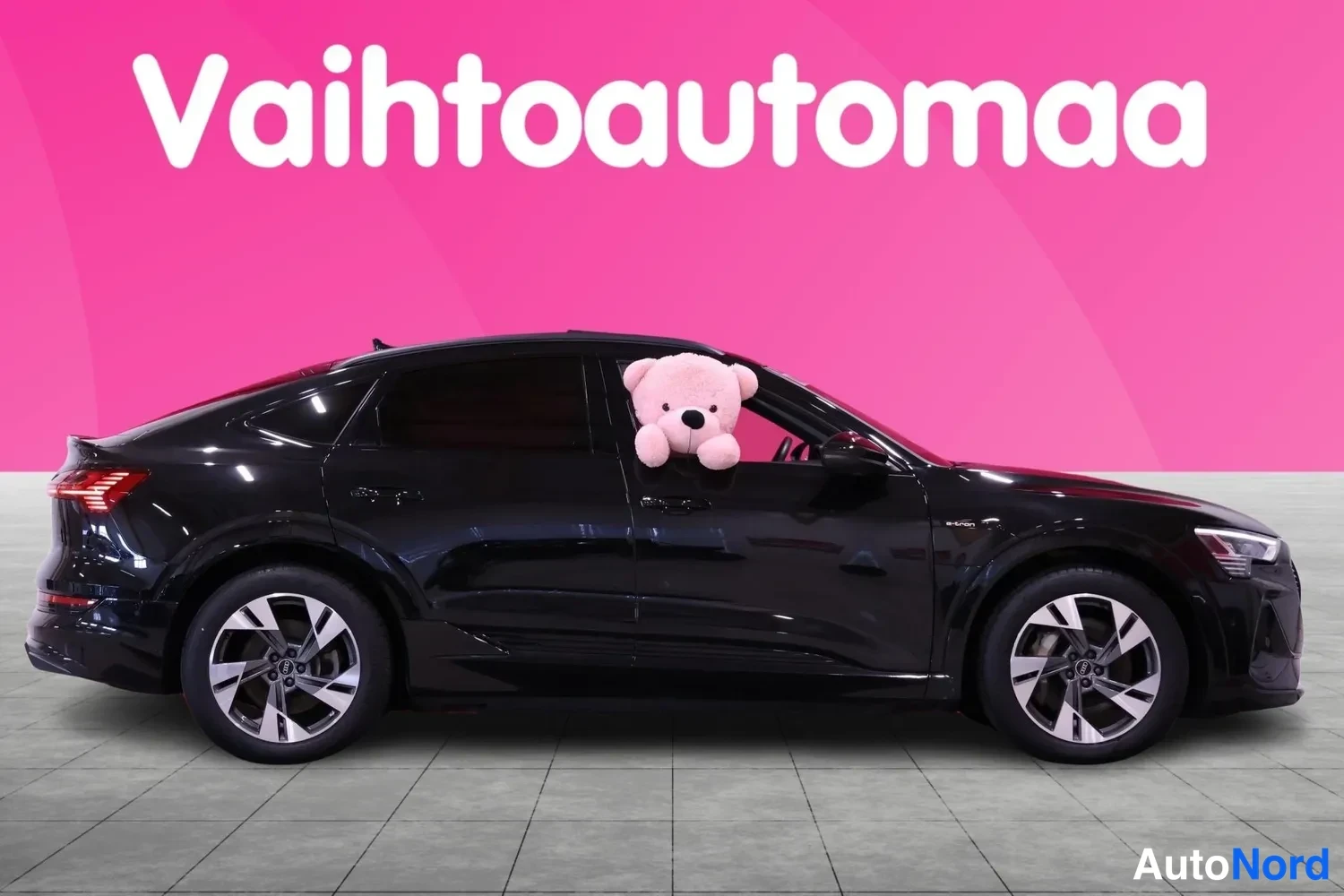 Takaviisto: Mustan Audi e-tron Sportbackin sivuprofiili, takavalot osittain näkyvät vasemmassa reunassa.