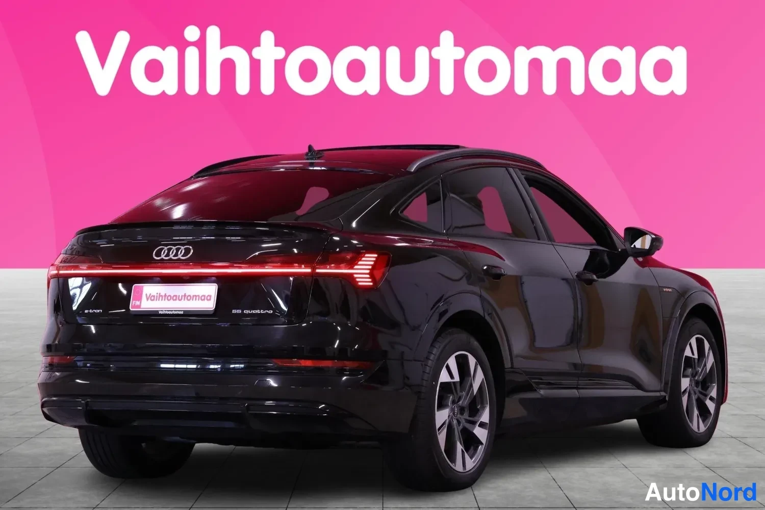 Takaviisto: Mustan Audi e-tron Sportbackin takapää ja oikea sivu, kokonaisvalaisinraidat ja Audi-merkki näkyvät.