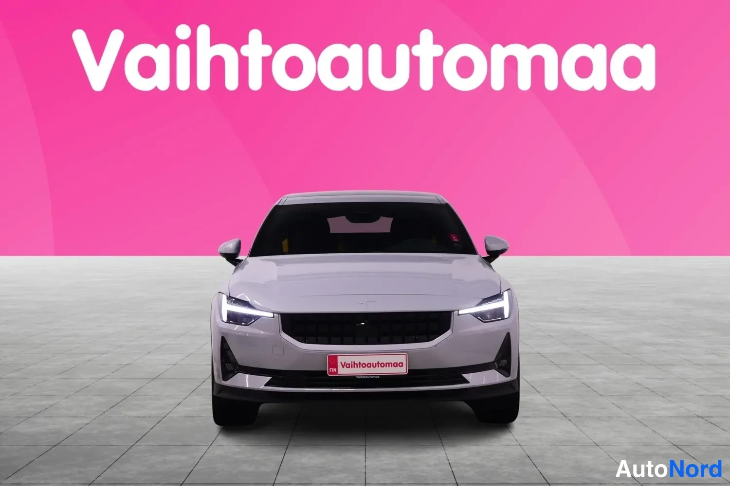 Edestä: Vaaleanharmaa Polestar 2 suoraan edestä päin studioissa.