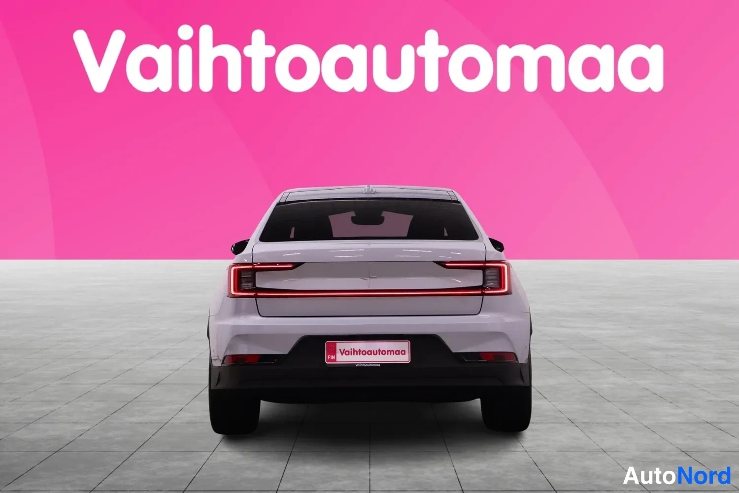 Takaa: Auton takaosäsuoraan: vaaleanharmaa takapaneeli, punainen valoviiva ja Vahtoautomaa-kyltti näkyvät pinkin taustaa vasten.