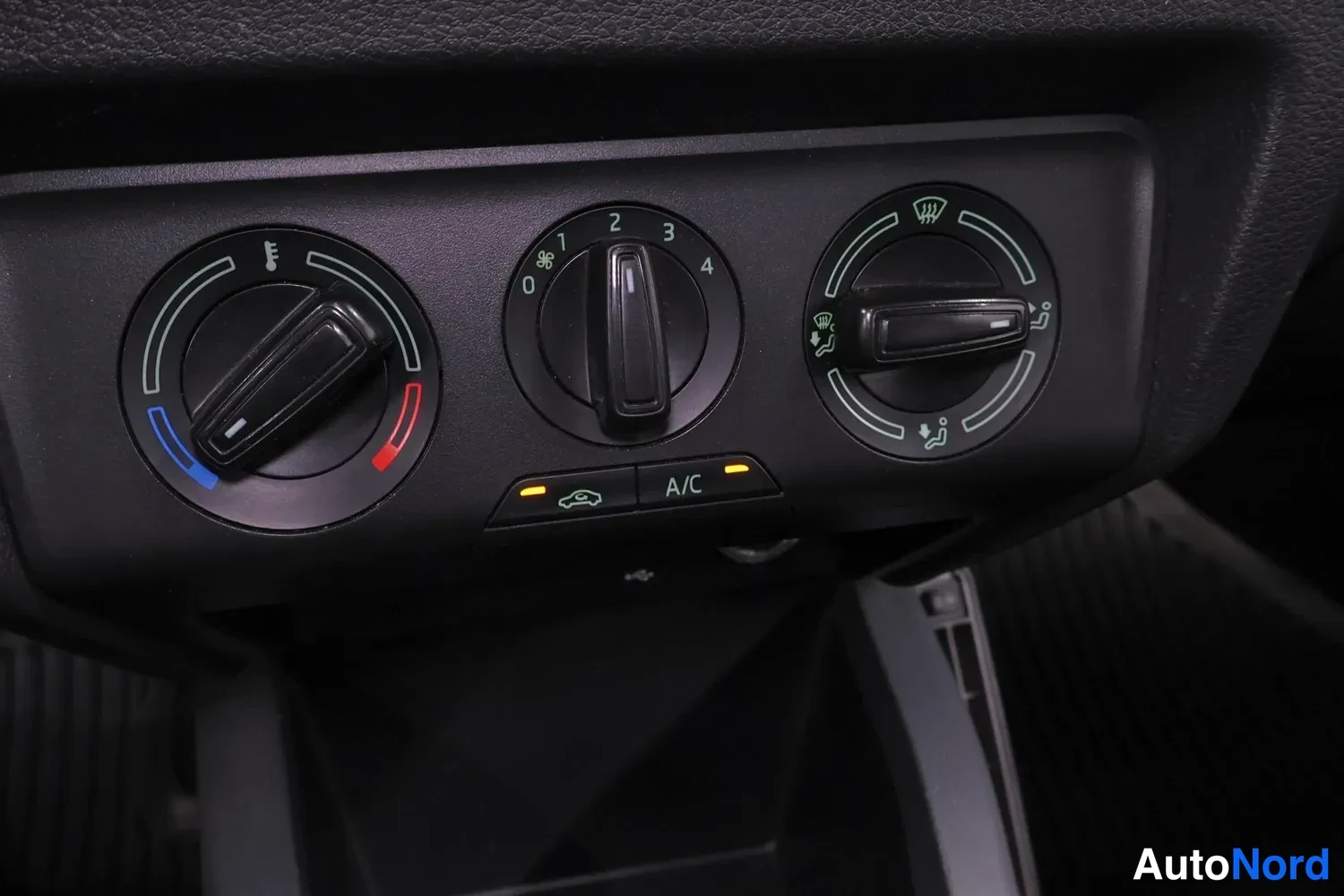 Ohjaamo: Close-up of manual climate control knobs and A/C switch. Three rotary dials control temperature, fan speed, and air direction.