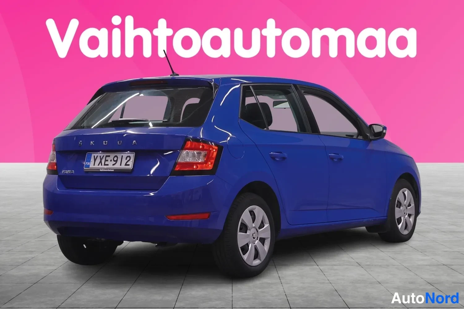 Takaviisto: Sininen Škoda Fabia takaa ja sivulta kuvattuna. Rekisterikilpi, takaluukun SKODA- ja FABIA-tekstit sekä takavalot näkyvissä.