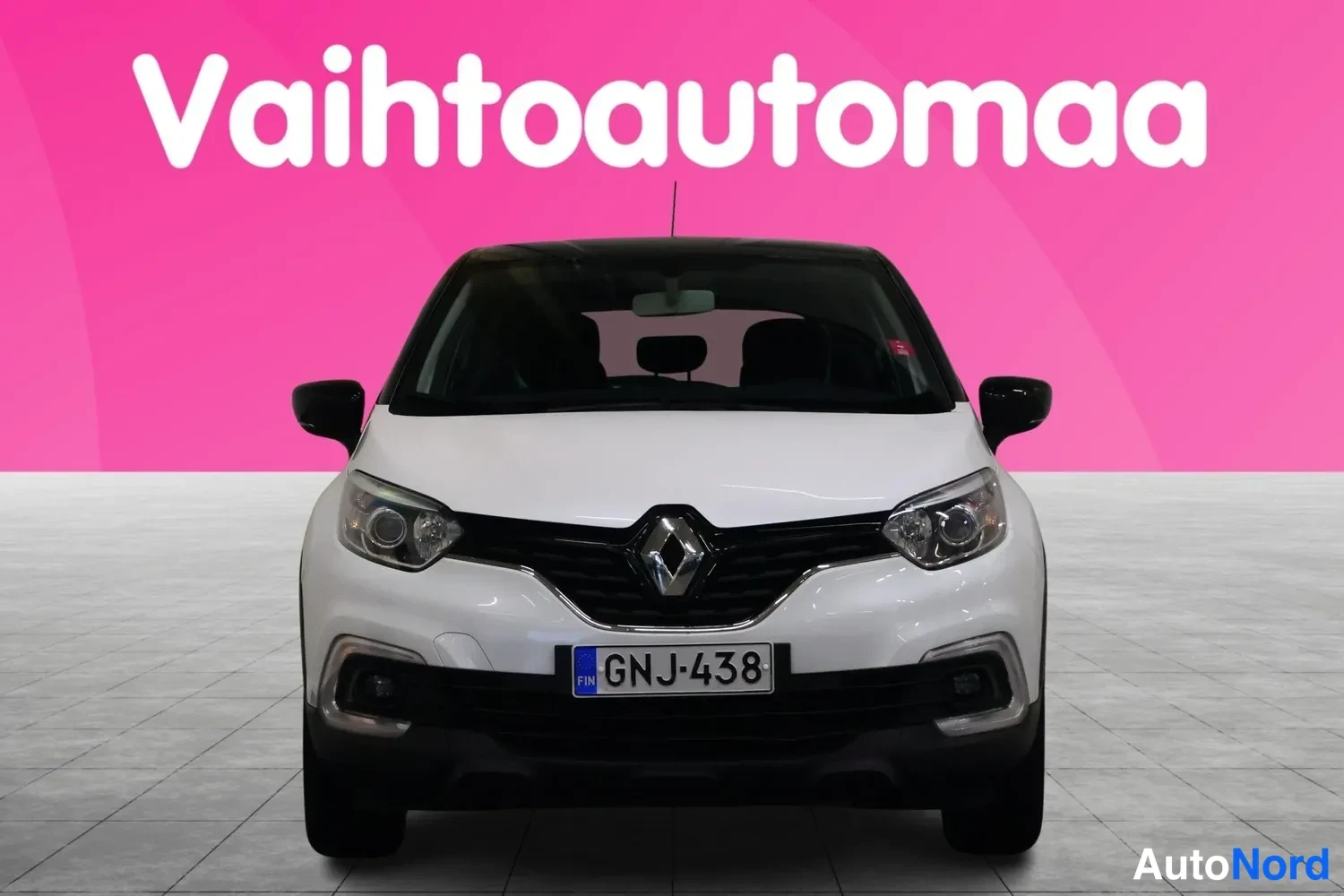 Edestä: Valkoinen Renault Captur suoraan edestäpäin, rekisteri, vaaleanpunaisella taustalla.