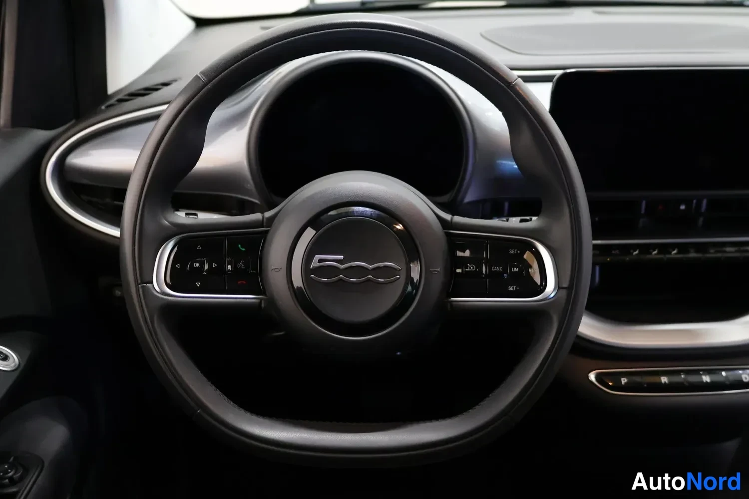 Yksityiskohta: Ohjauspyörä, jossa Fiat 500 -tunnus ja monitoimipainikkeet.