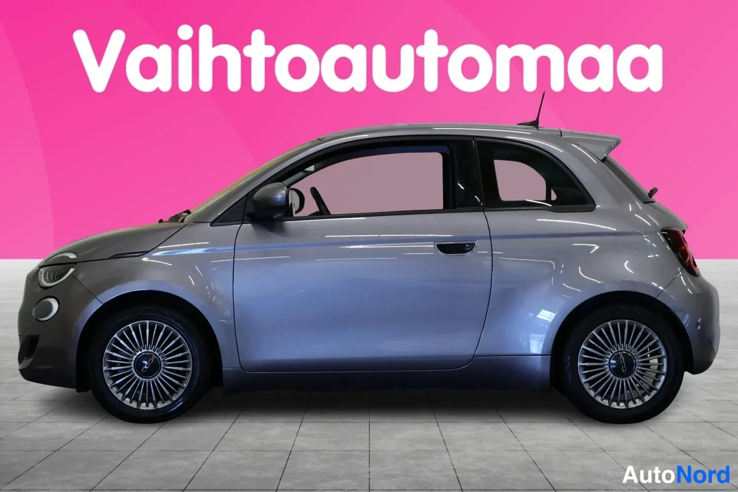 Etuviisto, nokka vasemmalle: Hopeanharmaa Fiat 500 sivulta vasemmalta kuvattuna studiotaustaa vasten.