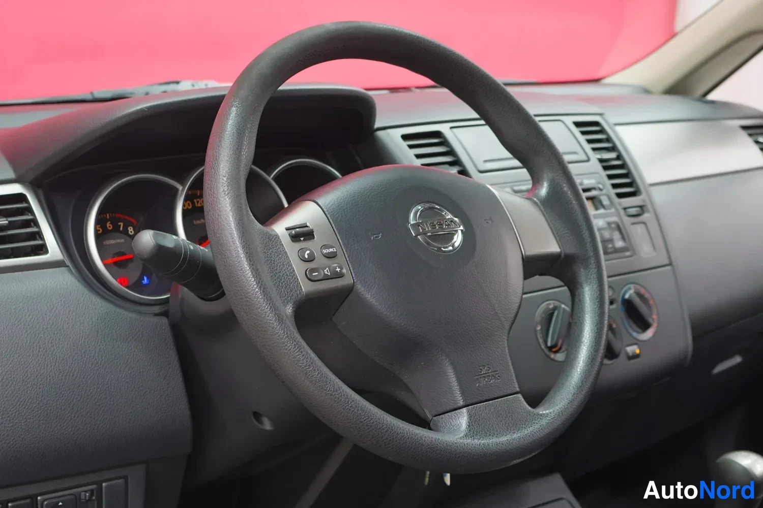 Yksityiskohta: Nissan-ohjauspyörä lähikuvassa mittariston edessä.