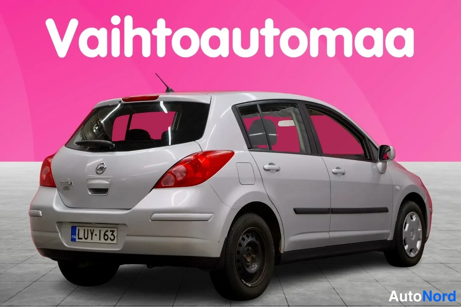 Takaviisto: Hopeanvärinen Nissan Tiida -viistoperä takaa oikealta kuvattuna, rekisterikilpi.