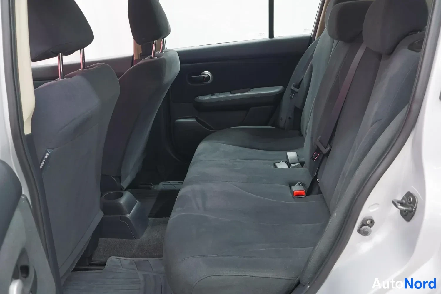 Muu: Nissan Tiidan takaistuimet tummalla kankaalla, ovenavaus vasemmalla.