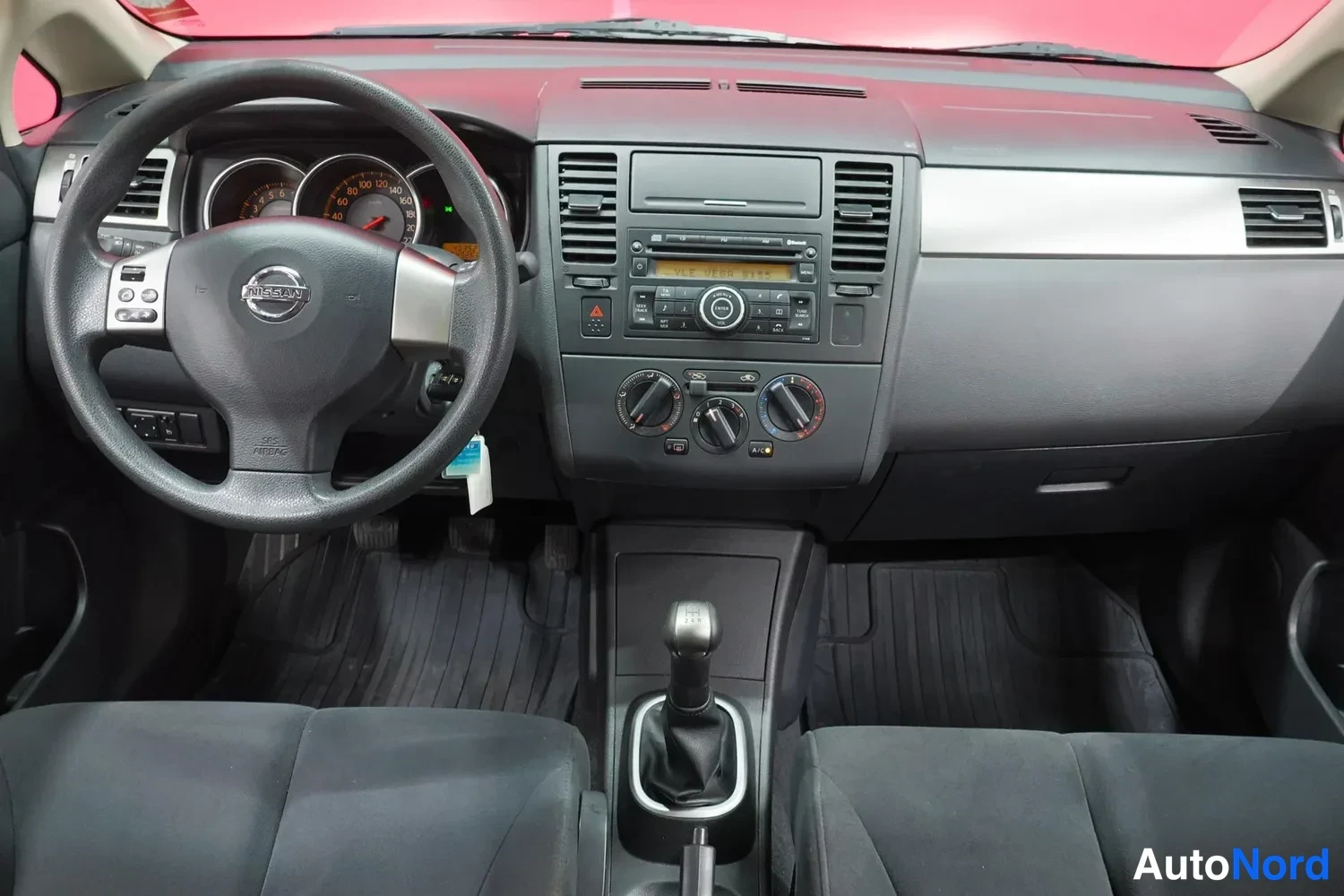 Yksityiskohta: Nissan Tiidan sisätilat: ohjauspyörä, kojelauta ja keskikonsoli manuaalivaihteistolla.