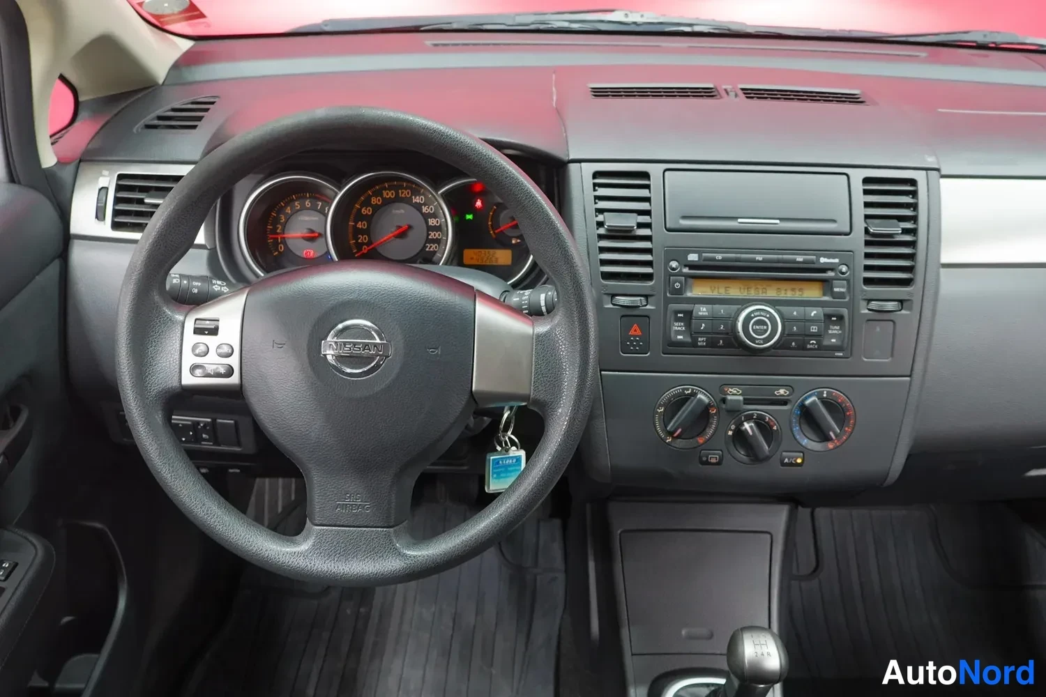 Yksityiskohta: Nissan Tiidan kuljettajan näkymä: ohjauspyörä, mittaristo ja radionäyttö.