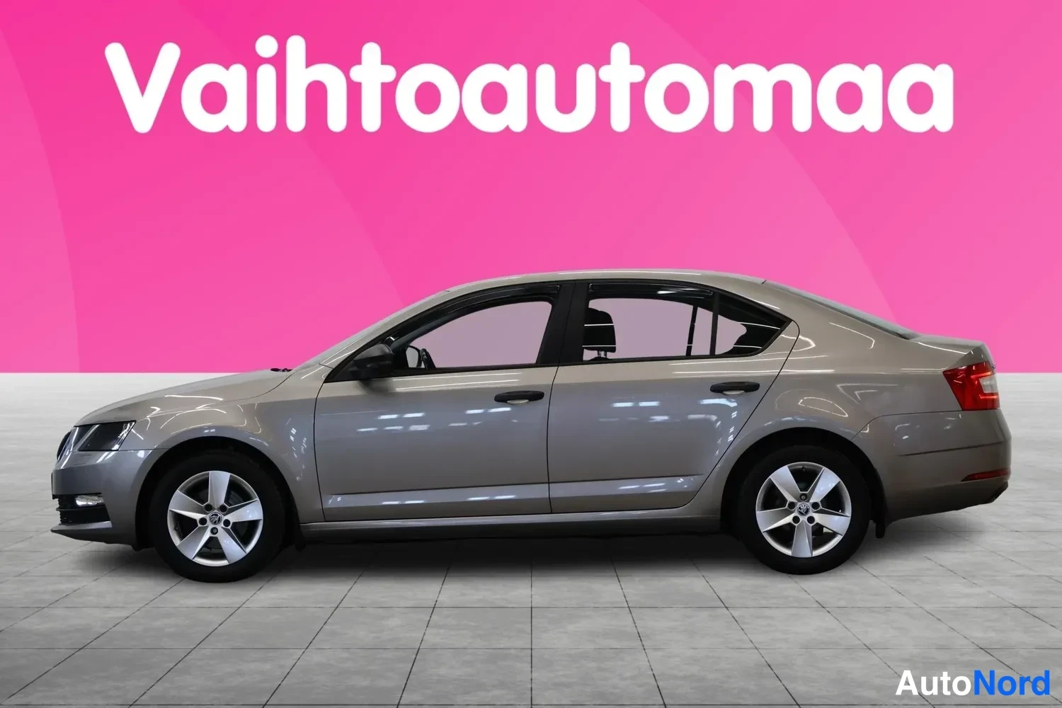 Etuviisto, nokka vasemmalle: Skoda Octavia -sedanin etukulma vasemmalta, beige-harmaa runko ja hopeavanteet kuvattuna studiotaustaa vasten.