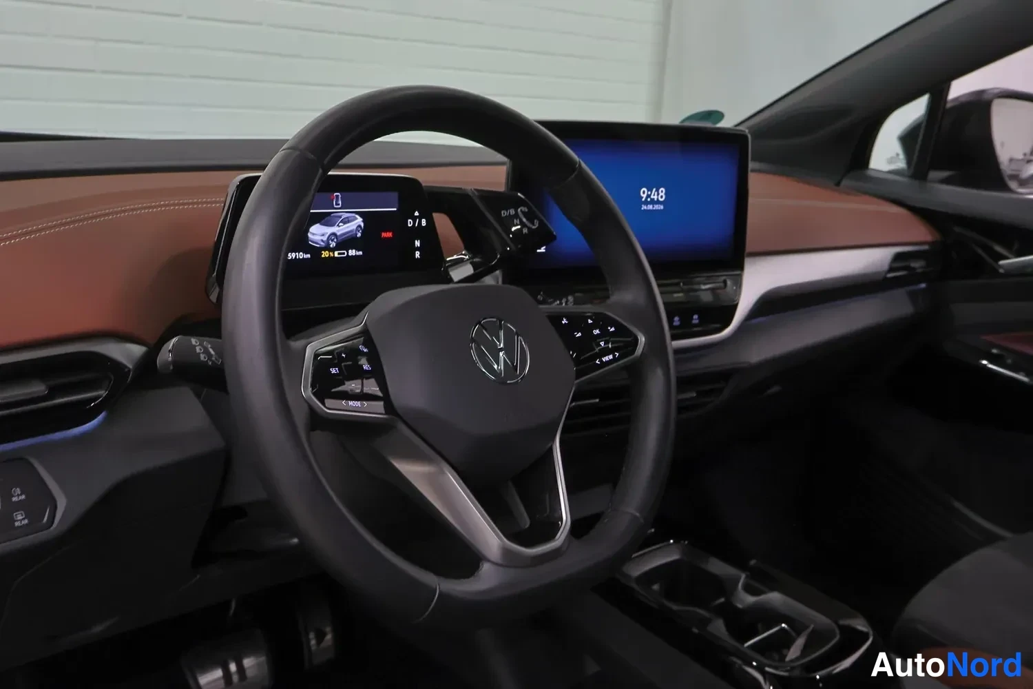 Muu: Ohjaamon näkymä: ohjauspyörä VW-merkillä, pieni digitaalinen mittaristo ja keskellä kosketusnäyttö, jossa kellonaika 9:48.