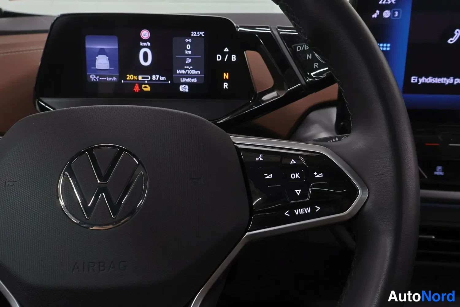 Muu: Ohjauspyörän Volkswagen-logo ja kuvanmyynti: mittariston näytöllä nopeus 0 km/h, akun varaus 20 % ja 87 km kantama, vaihdevalinnat D/B, N ja R.
