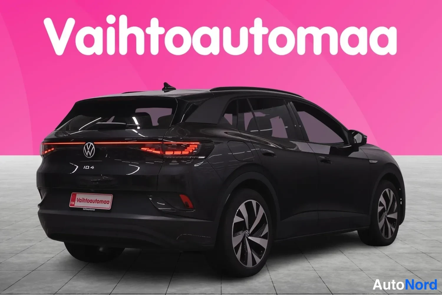Takaviisto: Mustan tilavaunuautomallin takanurkkakuva, punaiset takavalot ja VW-merkni pimeässä studiossa pinkillä taustalla.