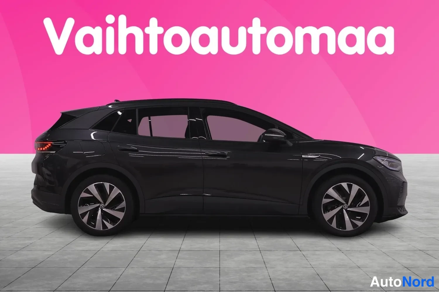 Etuviisto, nokka oikealle: Mustan SUV-mallin sivukuva koko autosta studiomaisessa tilassa, pinkki tausta ja Vahtoautomaa-logo.