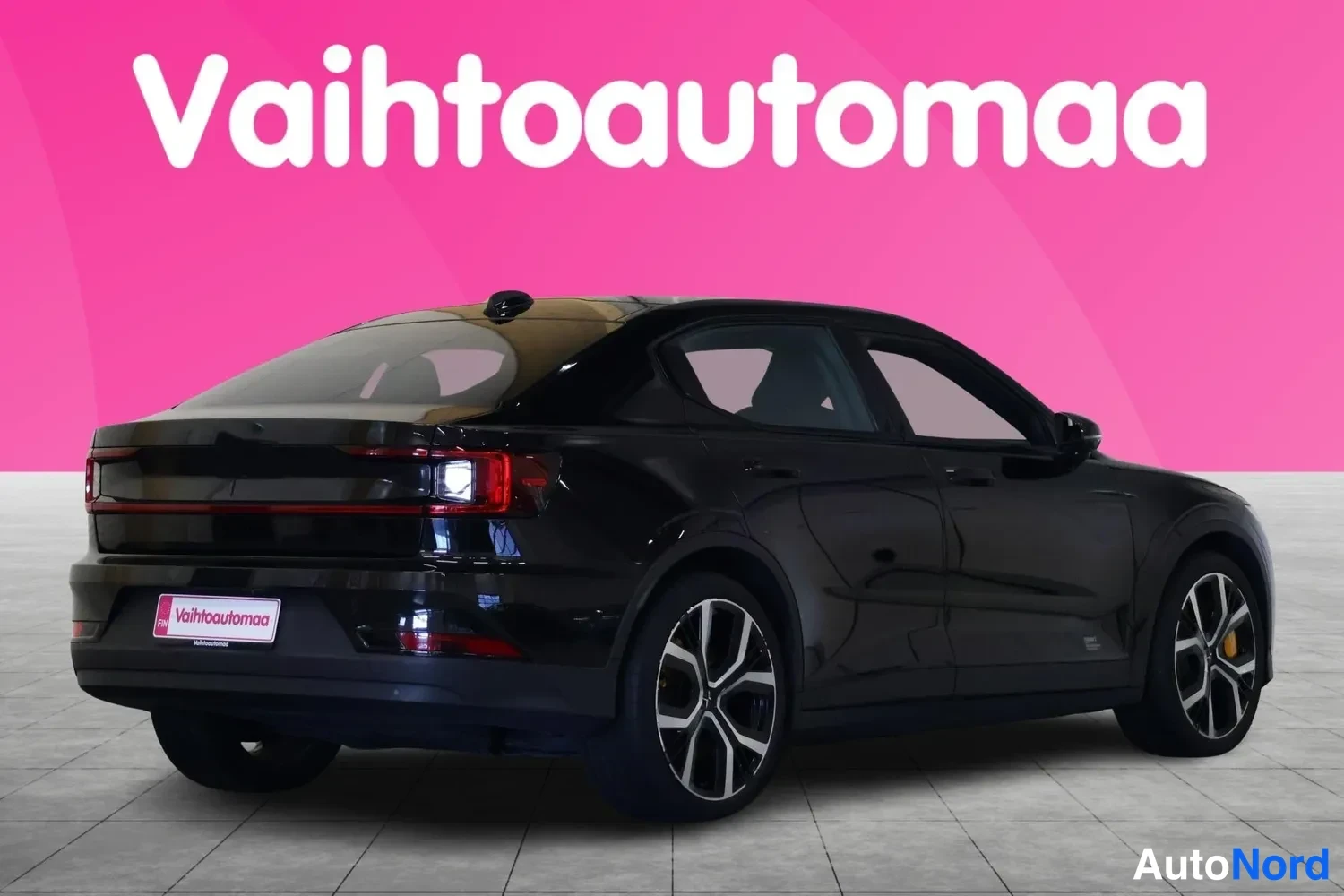Takaviisto: Mustan auton takakolmannesosakuva: takavalot, moottoritilan yläosa ja vasen kylki näkyvät, pinkki tausta.