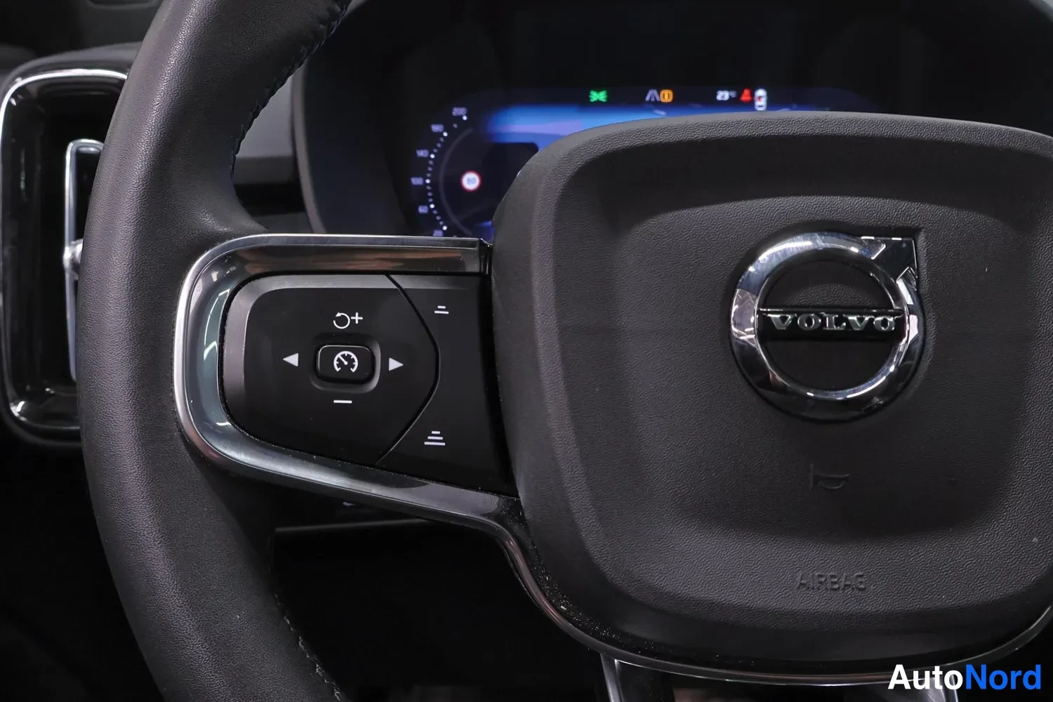 Edestä: Makrokula Volvon ohjauspyörästä: AIRBAG-teksti, VOLVO-logote ja risteilynohjaimen painikkeet.