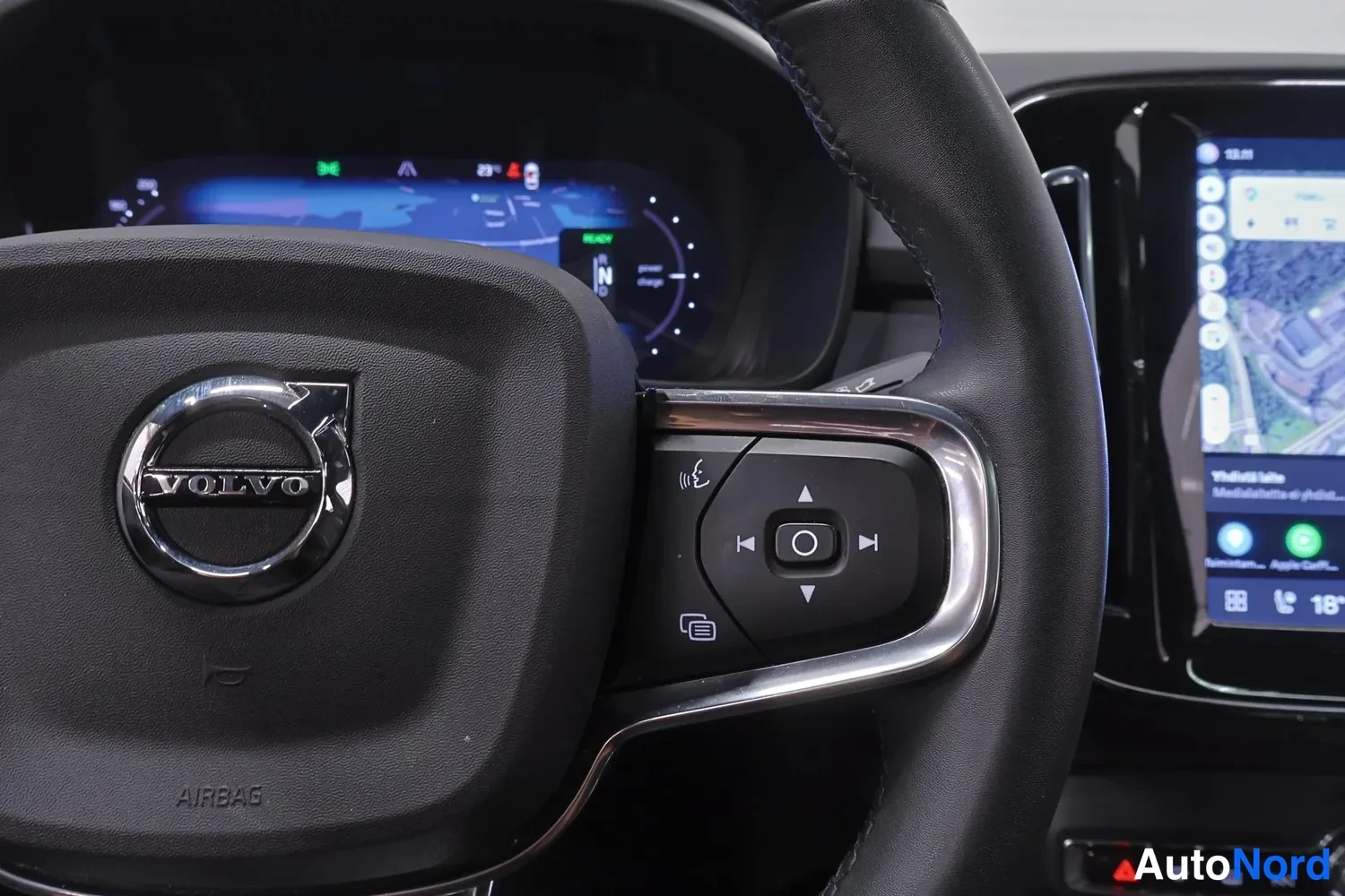 Muu: Volvo-ohjauspyörä merkinnällä AIRBAG ja monitoimanapeilla, taustalla osittain näkyvä mittaristonäyttö ja keskusnäyttö.