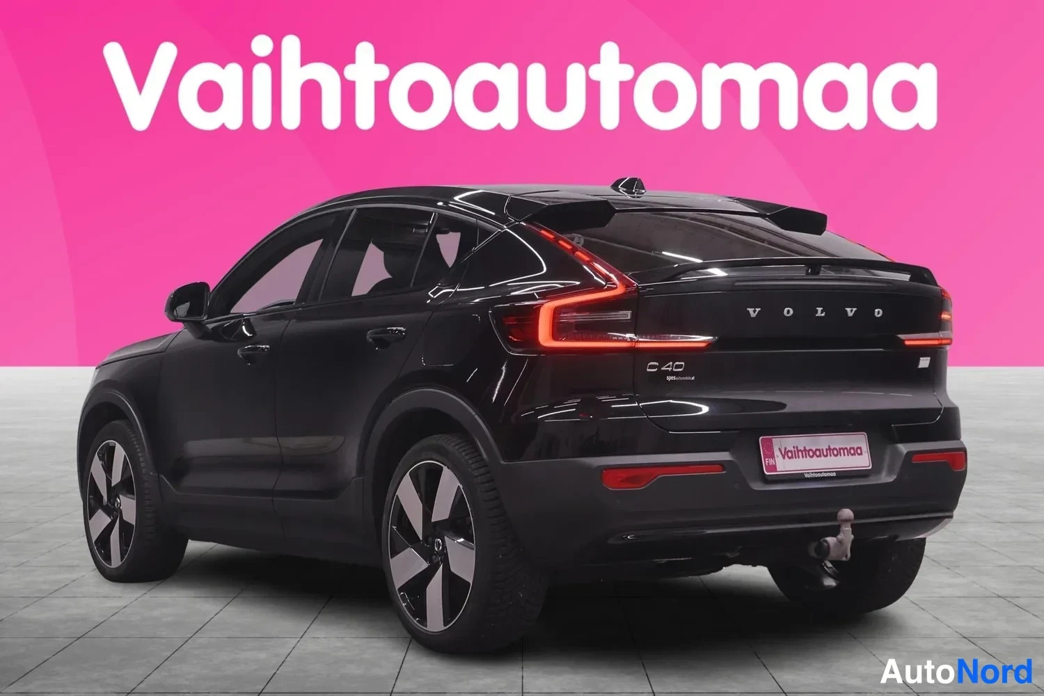 Takaviisto: Mustan henkilöauton takanäkymä viistosti, takavalojen punainen hehku ja VOLVO-teksti takaoven kannessa.