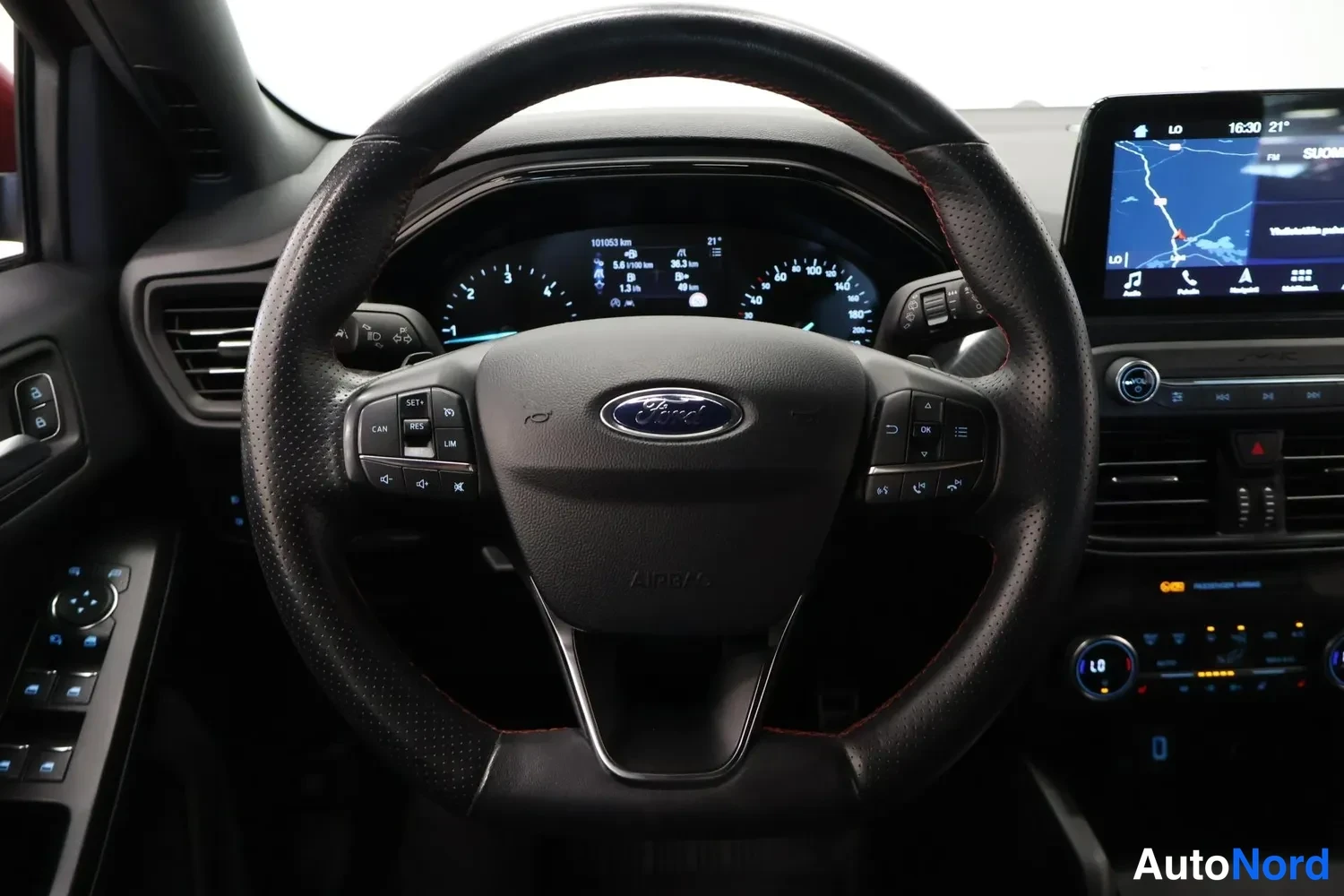 Yksityiskohta: Ohjaamon näkymä: Ford-merkkinen monitoimiohjauspyörä, digitaalinen mittaristo ja keskikonsolin karttanäyttö.