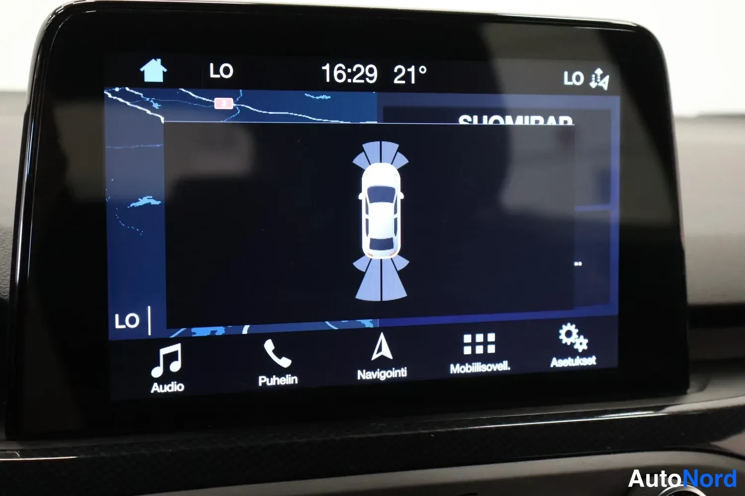 Muu: Ford Focusin infotainment-näyttö näyttää parkkitutkan autonäkymää ja radioasemaa SUOMIRAP.