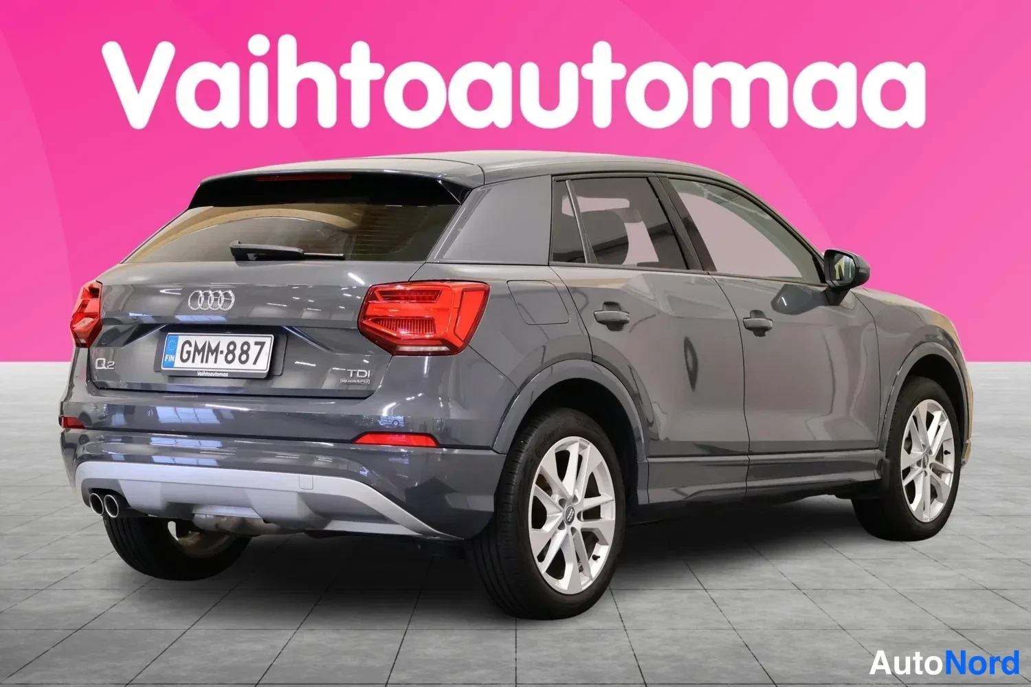 Takaviisto: Tummanharmaa Audi Q2 takaviistolta, rekisterikilpi, punaiset takavalot ja kattospoileri näkyvissä.