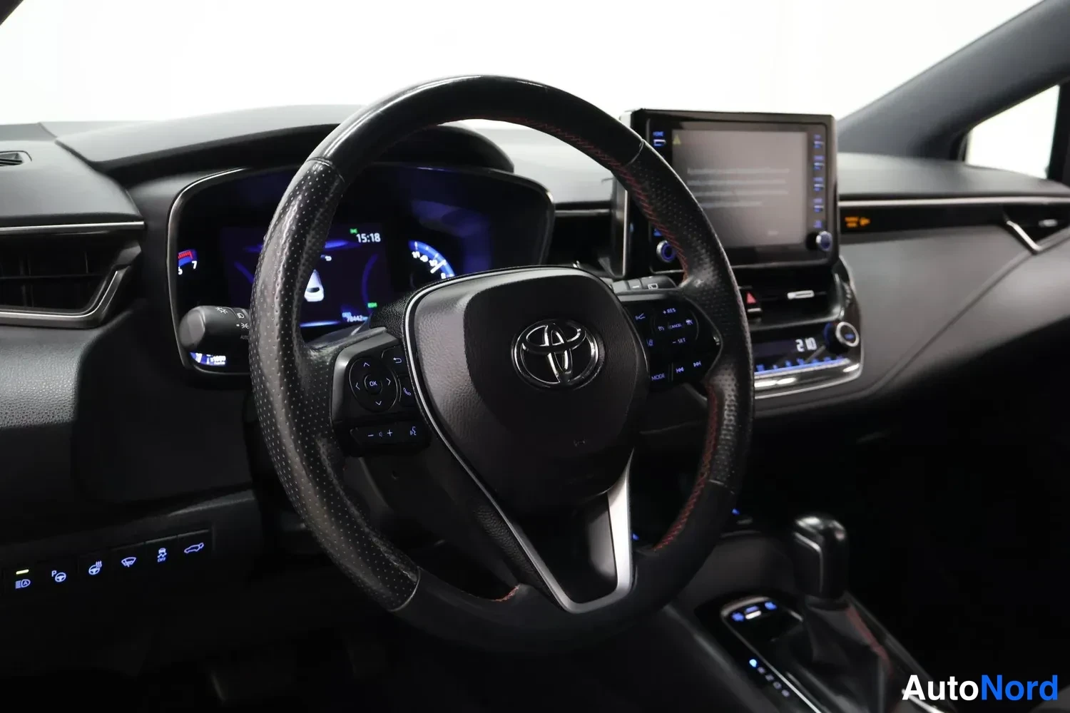 Muu: Kuljettajan näkökulma ohjaamosta: Toyota-merkkinen ohjauspyörä, osittain sulkeutuva näyttö ja digitaalinen mittaristo.