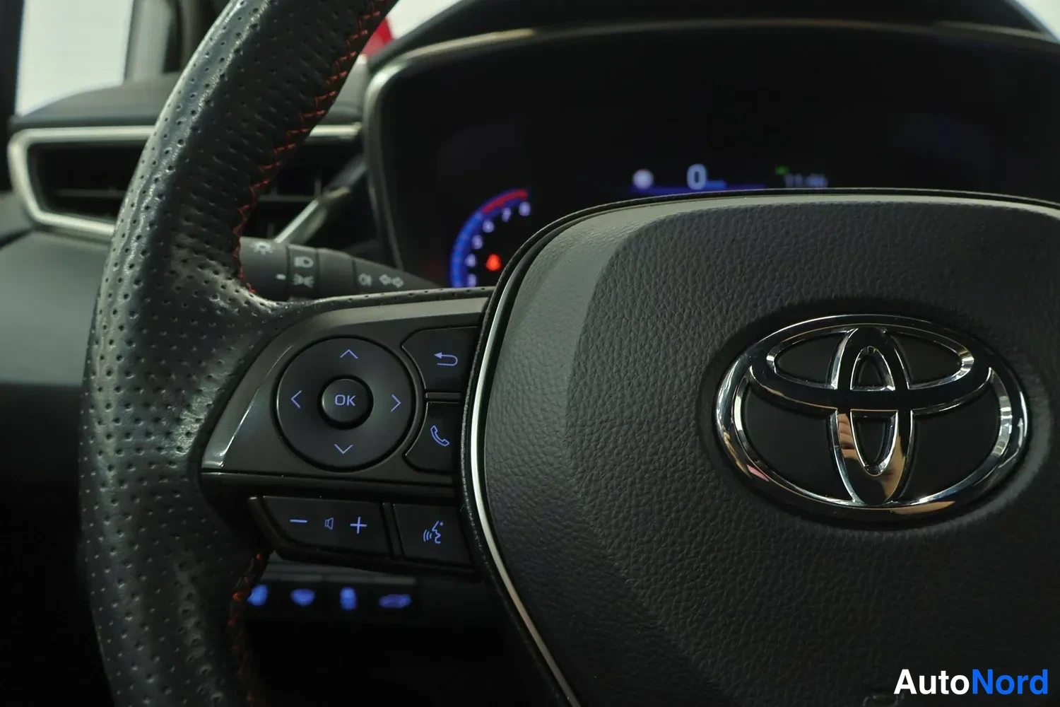 Edestä: Ohjauspyörän nappien lähikuva Toyota-logolla.