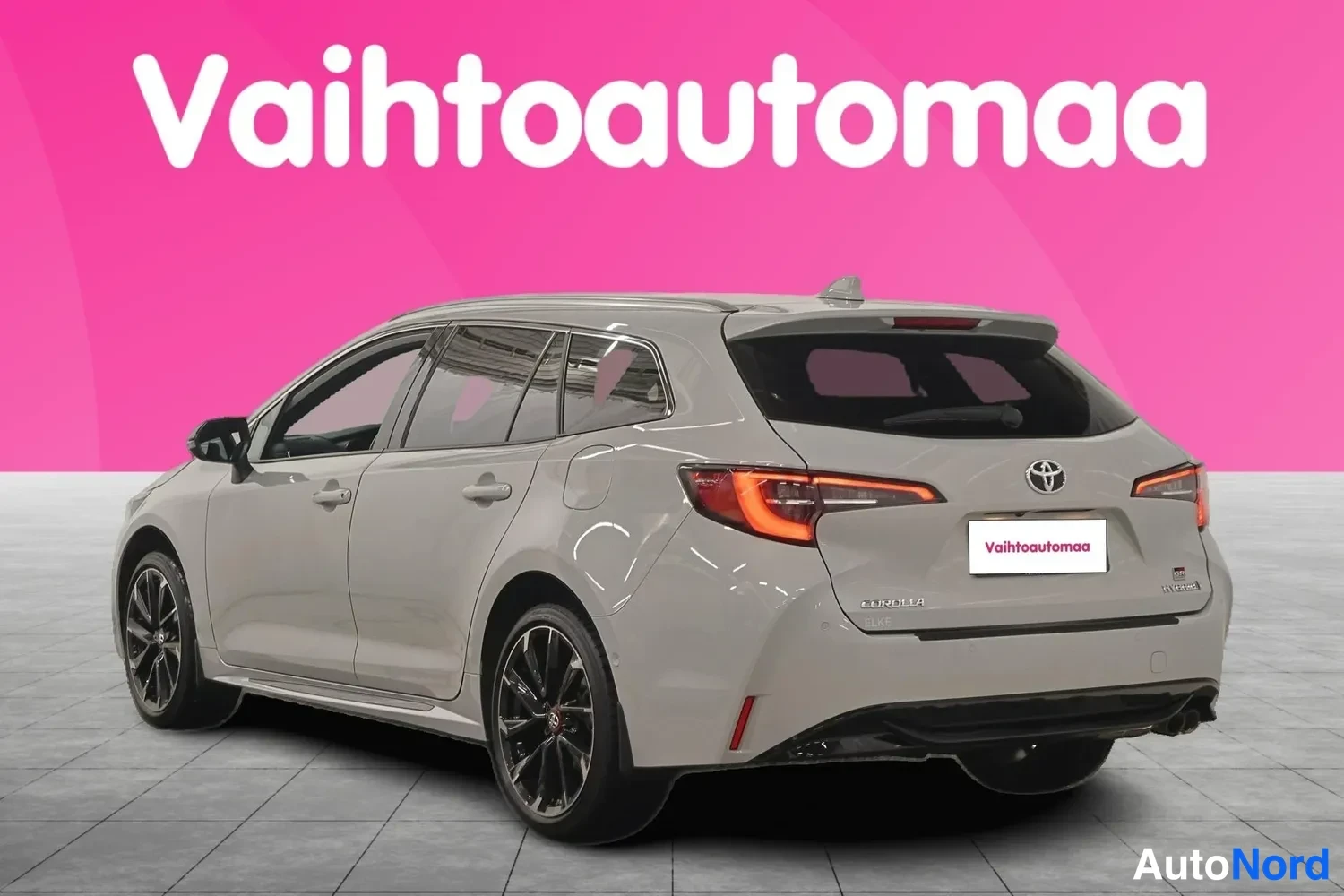 Takaviisto: Auton takaosa ja vasen sivu kolmannelta kulmalta; vaaleanharmaa farmarikorinen auto.