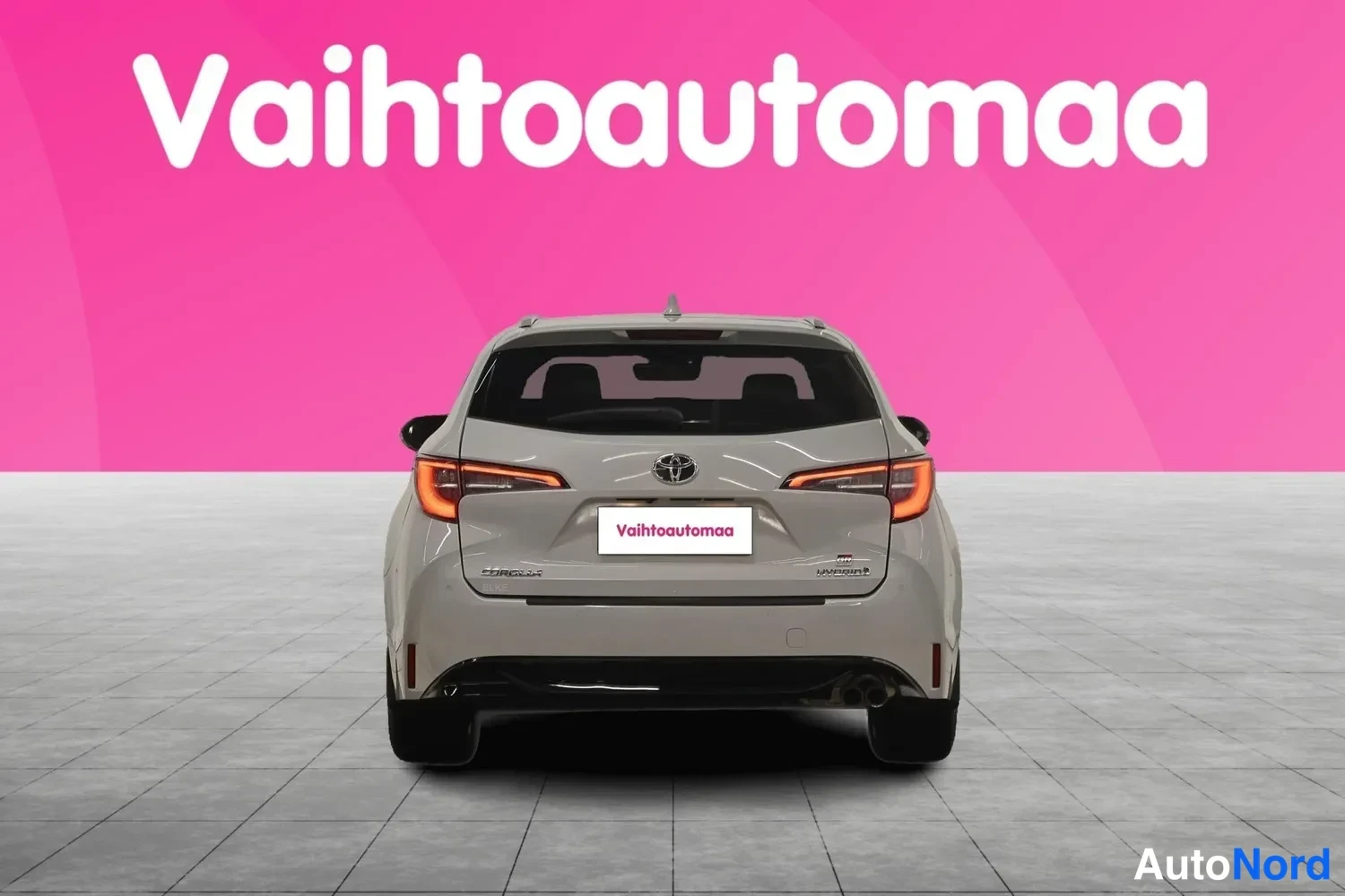 Takaa: Auton takaosa suoraan takaa; vaaleanharmaa farmarikorinen auto, Toyota-merkki ja takavaloja näkyvissä.