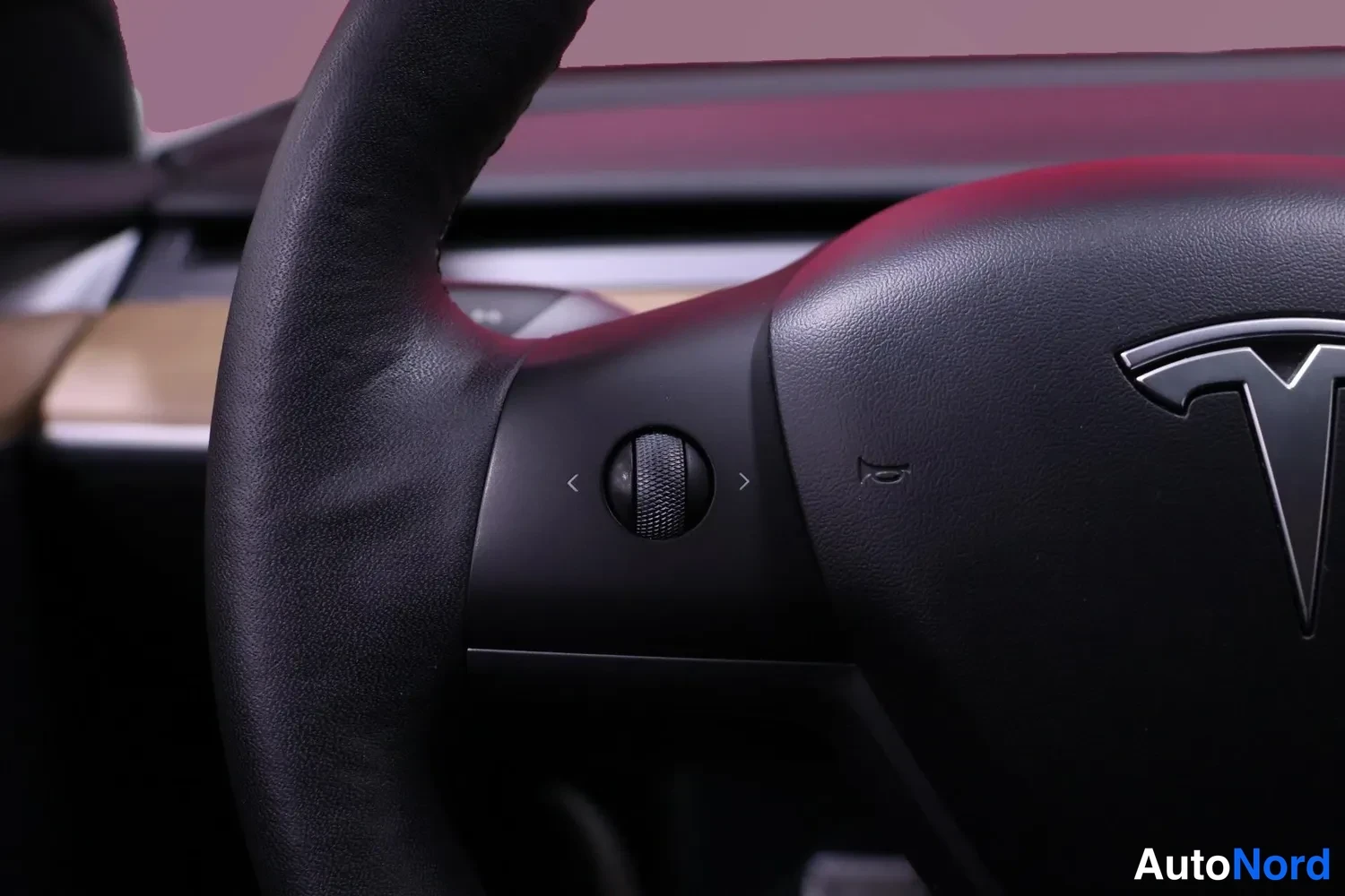 Muu: Ohjauspyörän vasen puoli: Tesla-logo, vasen säätörulla ja nuolipainikkeet.