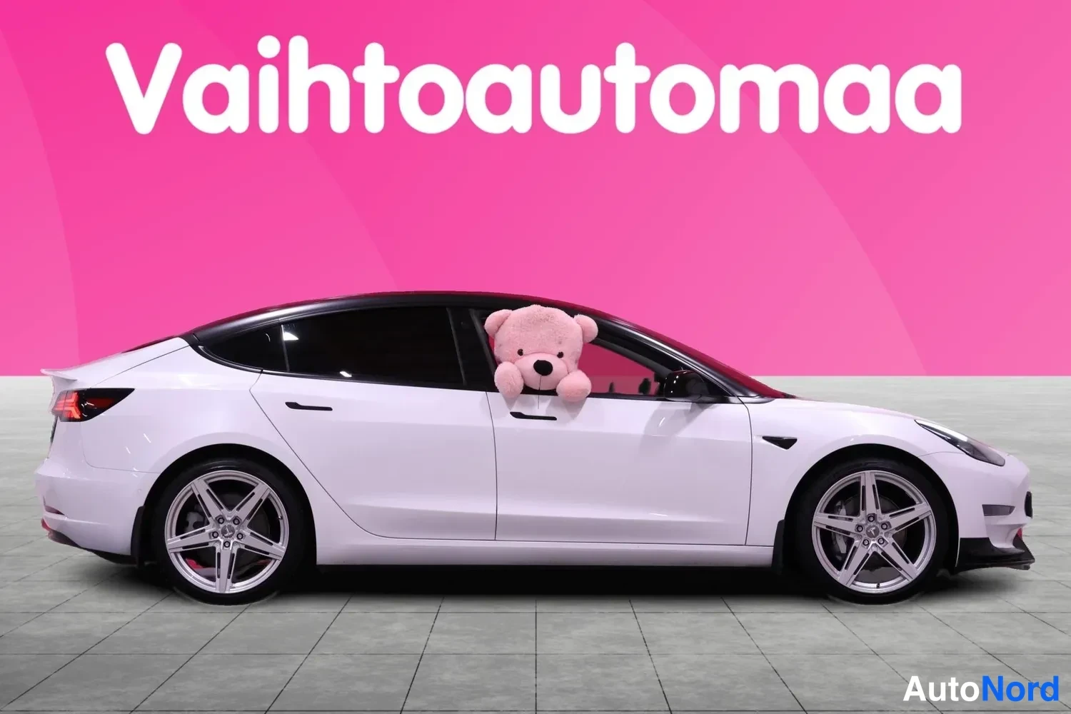 Sivulta: Valkoinen Tesla Model 3 -henkilöauto sivusta oikealta kuvattuna.