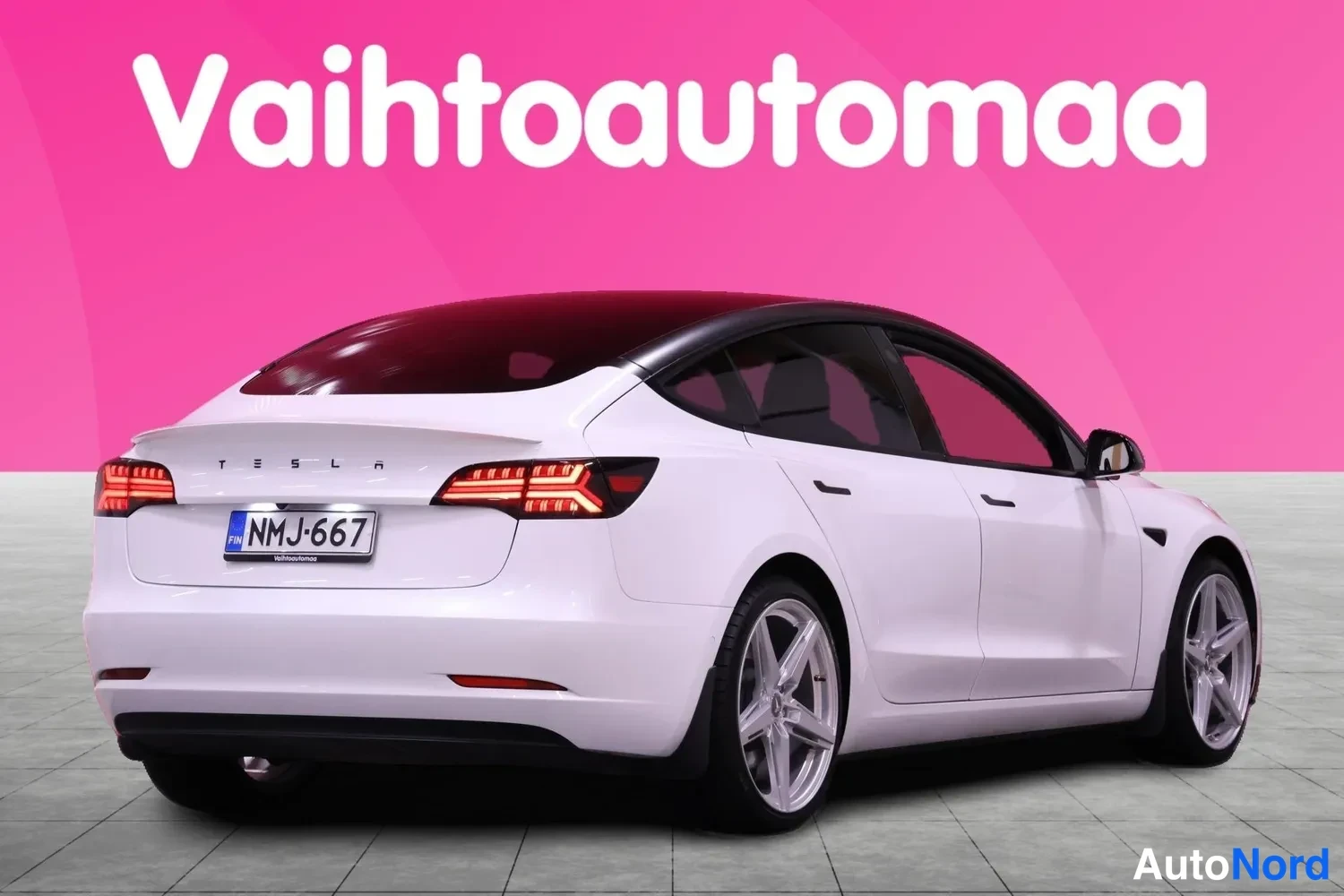 Takaviisto: Valkoinen Tesla Model 3 -henkilöauto takaa vasemmalta kuvattuna, rekisteritunnus.